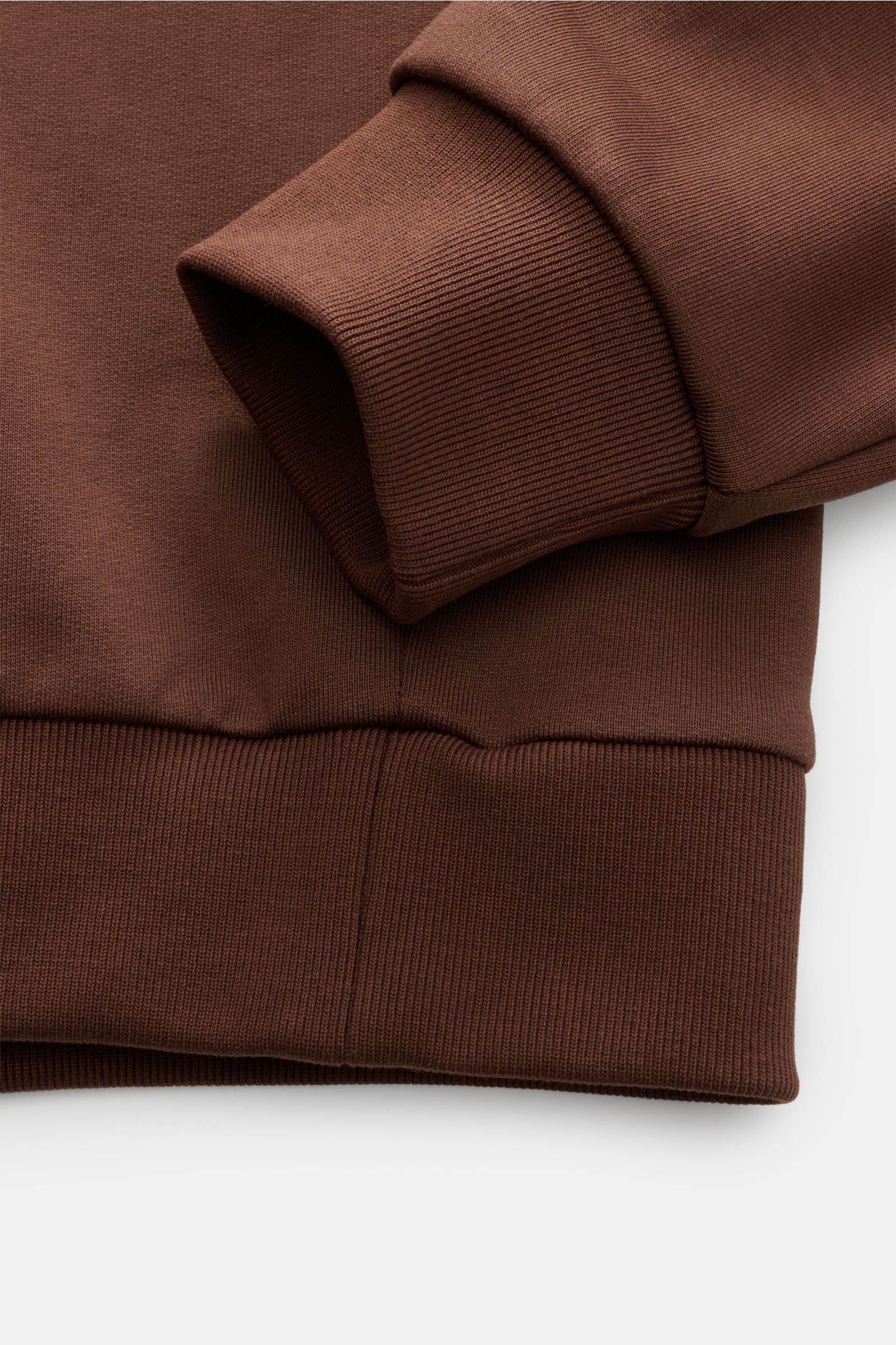 Nahaufnahme des braunen A.P.C. Rundhals-Sweatshirts 'Standard Rue Madame' mit weichem Griff, Rippbündchen und Logo-Stitching, von oben fotografiert.