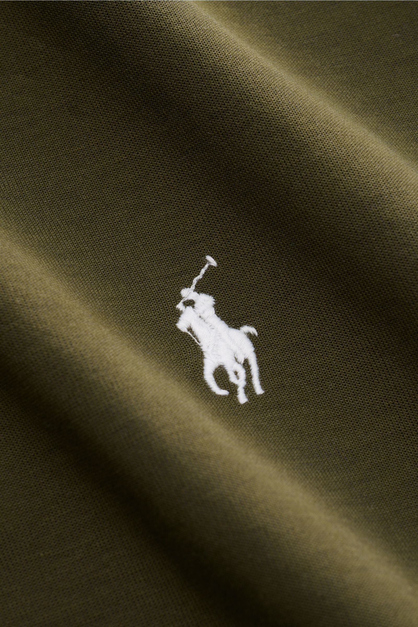 Close-up front view of Polo Ralph Lauren Sweat-Troyer dark olive showing white embroidered polo player logo on soft cotton and microfiber fabric.

Für vollen Komfort sorgt angenehm weicher Jersey aus Baumwolle und hochwertiger Microfaser, der den sport
