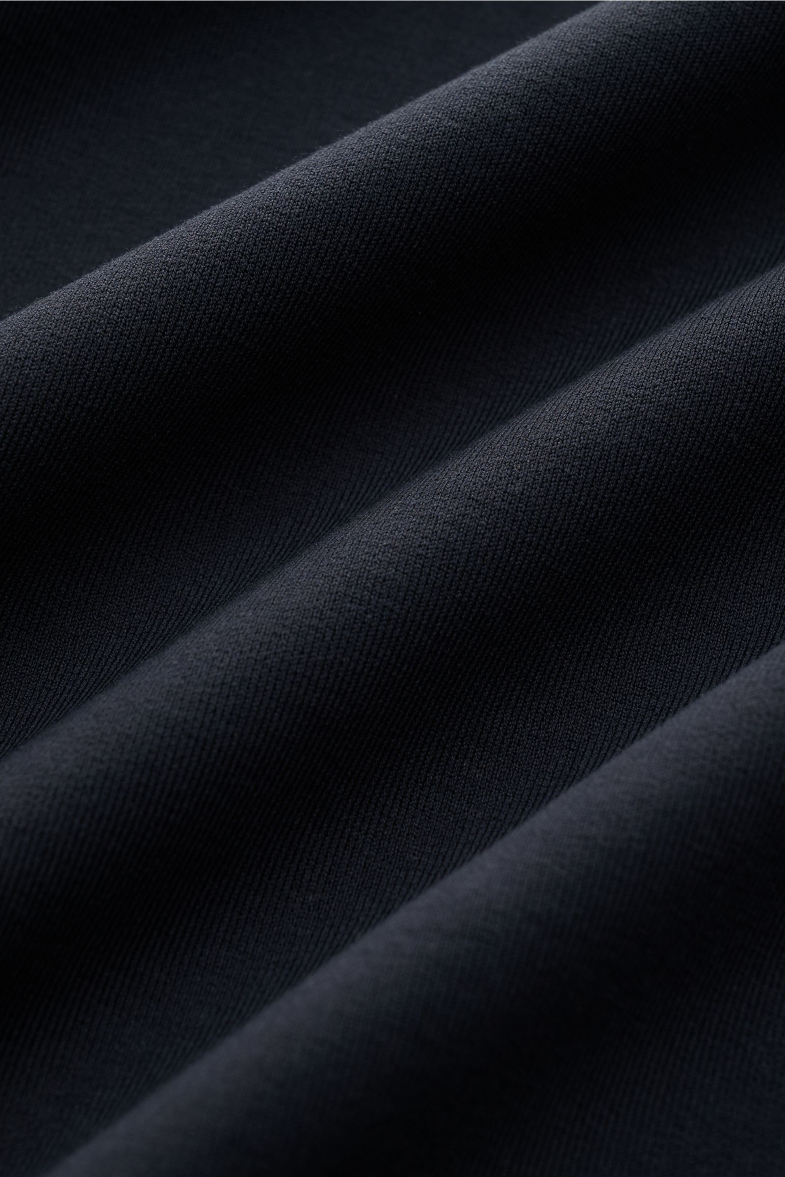 Nahaufnahme des dunkelblauen Stoffes vom Stefan Brandt Rundhals-Longsleeve 'Eder' dark navy, Jersey aus Pima-Baumwolle, komfortabler Stretch-Anteil, weicher Griff, Slim Fit, Rundhalsausschnitt, breites Saumbündchen, fotografiert aus seitlicher Perspektive