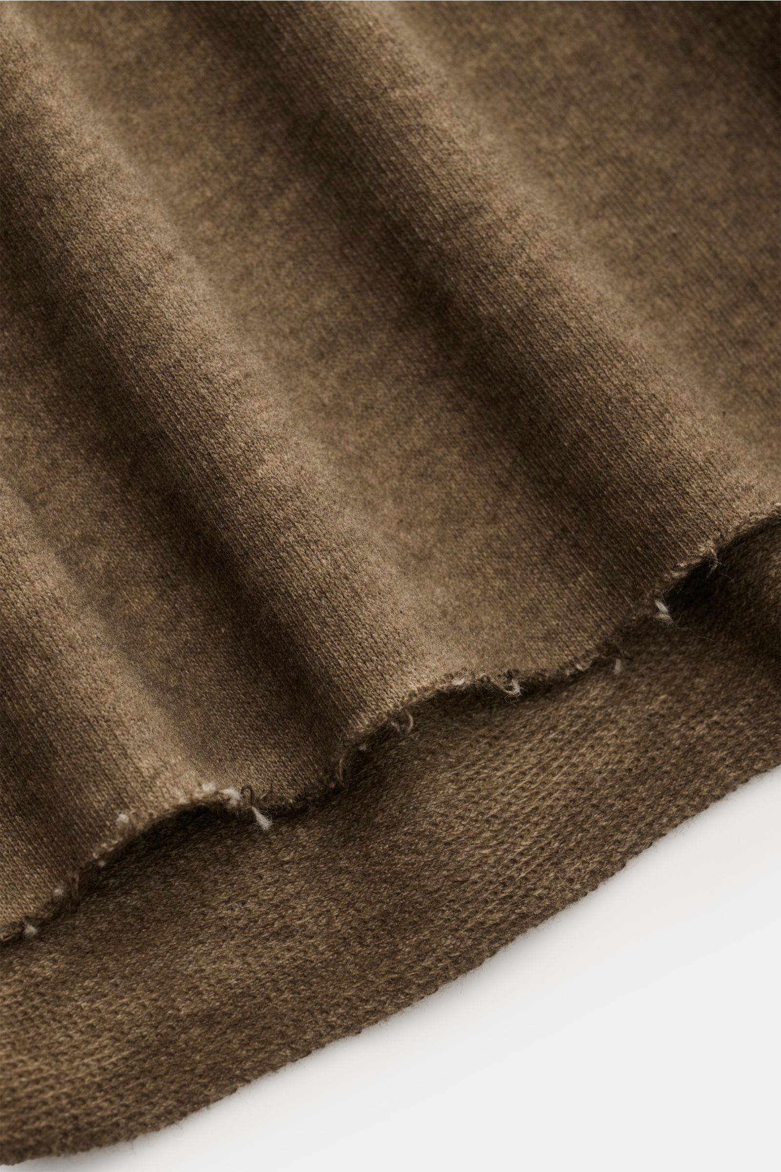 Close-up of the hem edge of the Kiefermann Crew neck sweatshirt 'Achko' dark olive mottled, showing the open edges and soft, garment-dyed cotton fabric from a side angle. The crew neck sweatshirt 'Achko' by KIEFERMANN is the perfect mix of long sleeve and