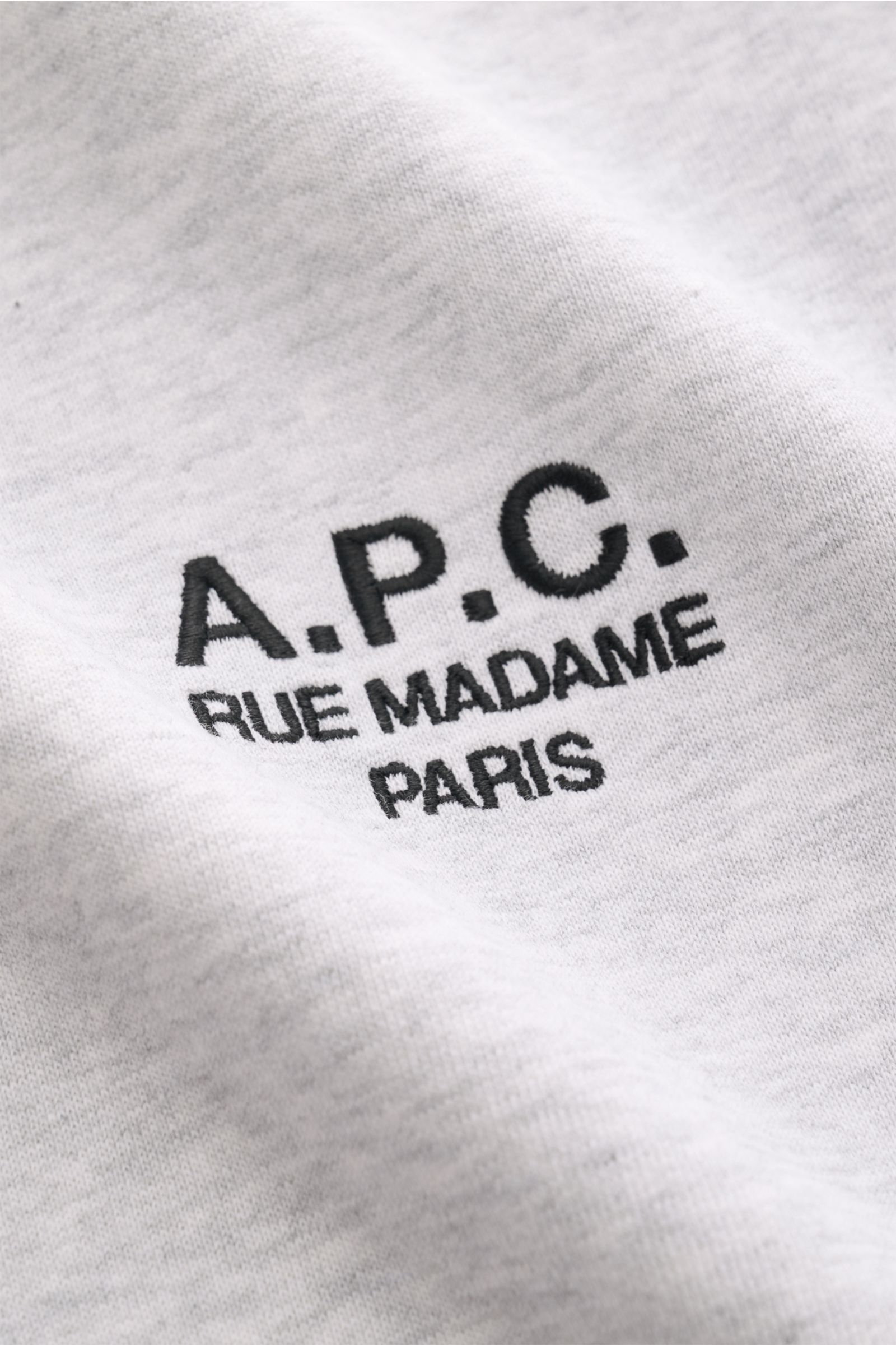 Close-up front view of the A.P.C. Rundhals-Sweatshirt 'Standard Rue Madame' grau meliert showing the black embroidered logo on soft, light gray cotton fabric.

Streetwear mit französischem Flair: Das minimalistische Sweatshirt 'Standard Rue Madame' von