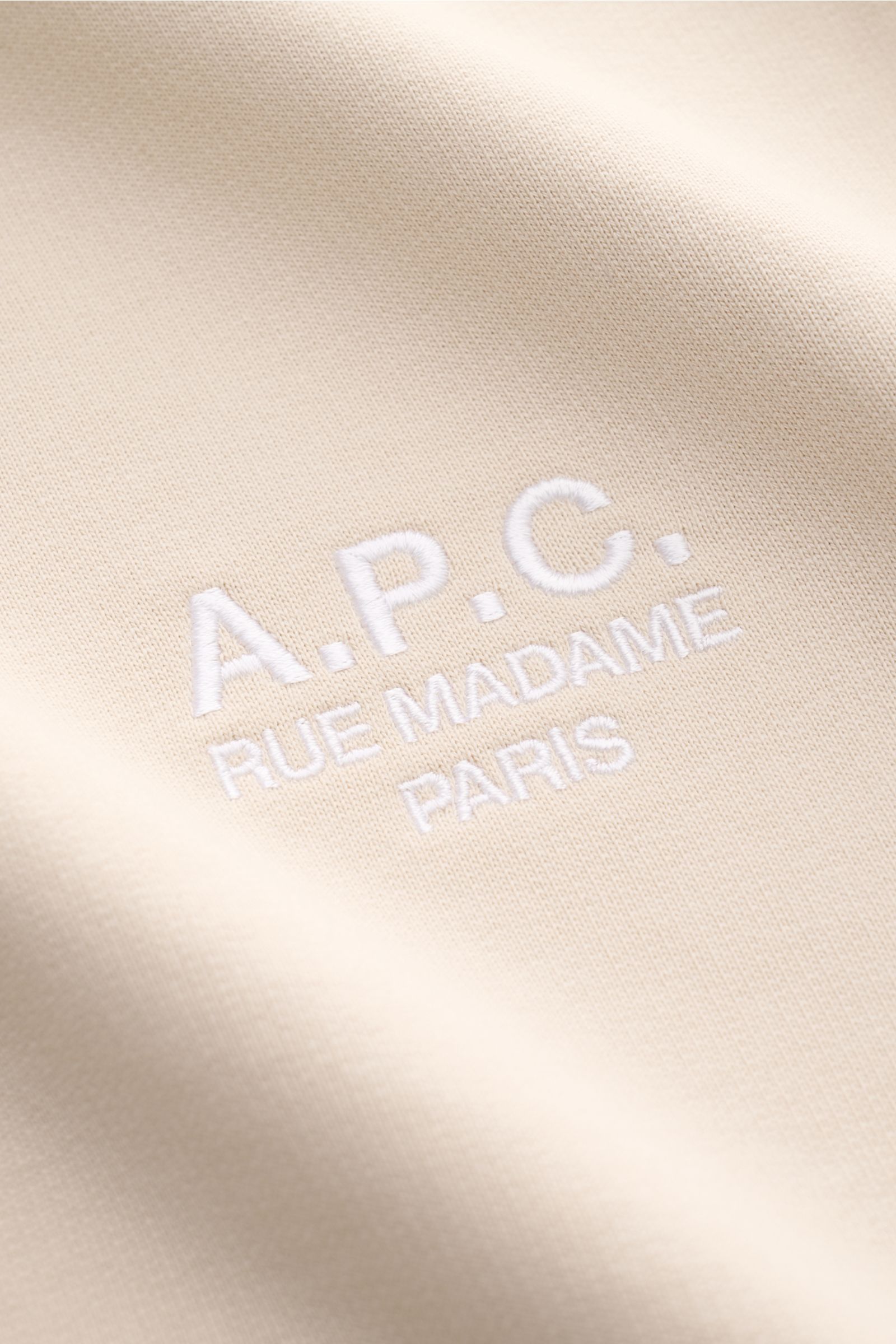 A.P.C. Rundhals-Sweatshirt 'Standard Rue Madame' sand, Detailaufnahme des farblich abgesetzten weißen Logo-Stitchings auf leicht elastischem Baumwoll-Sweat.