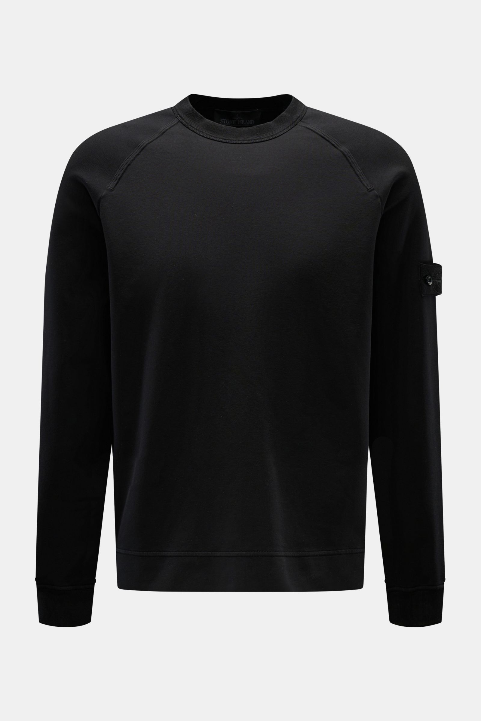Stone Island Sweatshirt 'Ghost Piece' schwarz, frontal fotografiert, aus elastischer Baumwolle mit tonalem Kompass-Badge am Ärmel, Rundhalsausschnitt, Raglanärmel, Regular Fit.