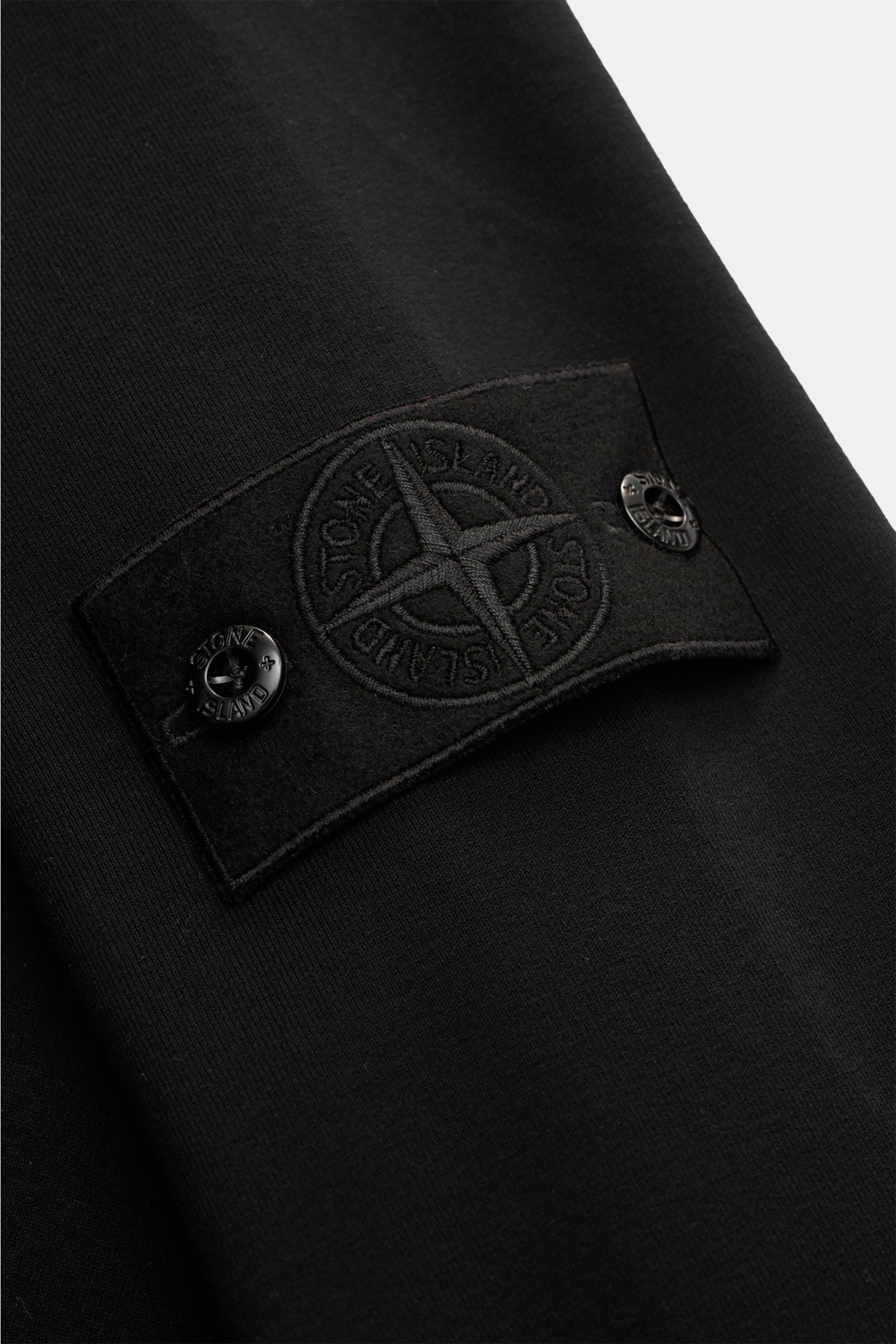 Stone Island Sweatshirt 'Ghost Piece' schwarz, Nahaufnahme des tonalen Kompass-Badges am Ärmel aus elastischer Baumwolle mit weichem Griff.
