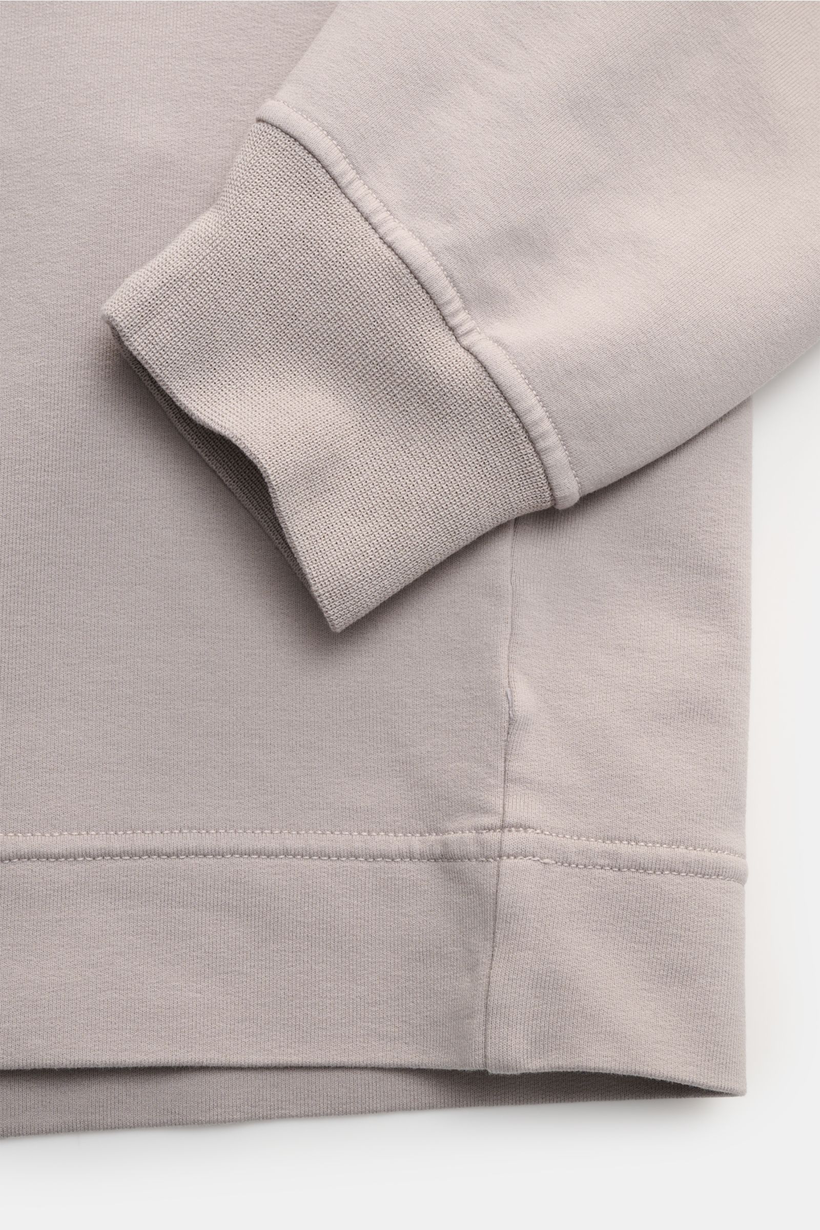 Close-up front view of the cuff and hem of the Stone Island Sweatshirt 'Ghost Piece' grau, made of elastic cotton with a tonal compass badge on the sleeve. STONE ISLAND bietet mit diesem Sweatshirt aus elastischer Baumwolle mit tonalem Kompass-Badge am