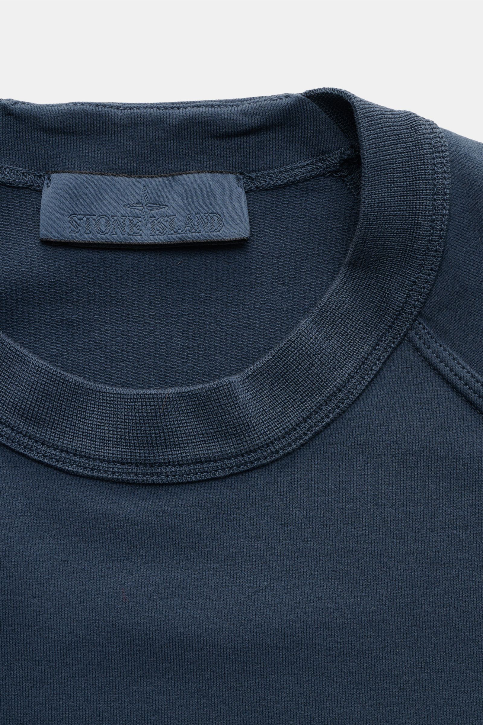 Close-up front view of Stone Island Sweatshirt 'Ghost Piece' graublau neckline showing soft, slightly elastic cotton fabric with tonal compass badge on sleeve, raglan sleeves, round neck, regular fit, and comfortable cuffs for casual wear. STONE ISLAND
