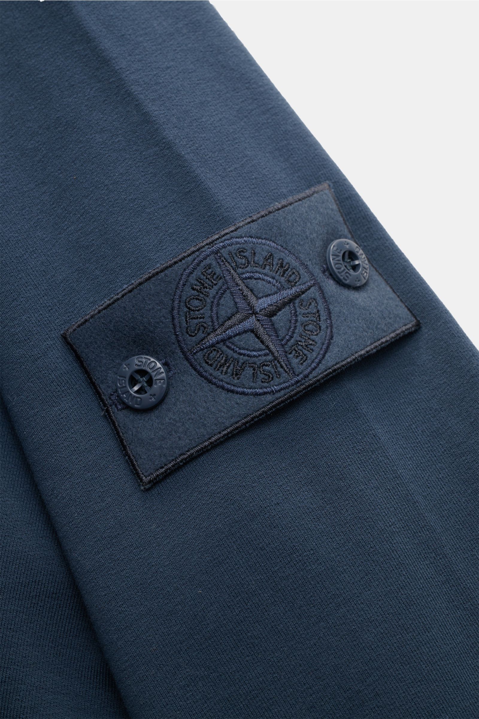 Close-up, angled view of the Stone Island Sweatshirt 'Ghost Piece' graublau showing its tonal compass badge on the sleeve, made of soft, slightly elastic cotton fabric.

STONE ISLAND bietet mit diesem Sweatshirt aus elastischer Baumwolle mit tonalem Ko