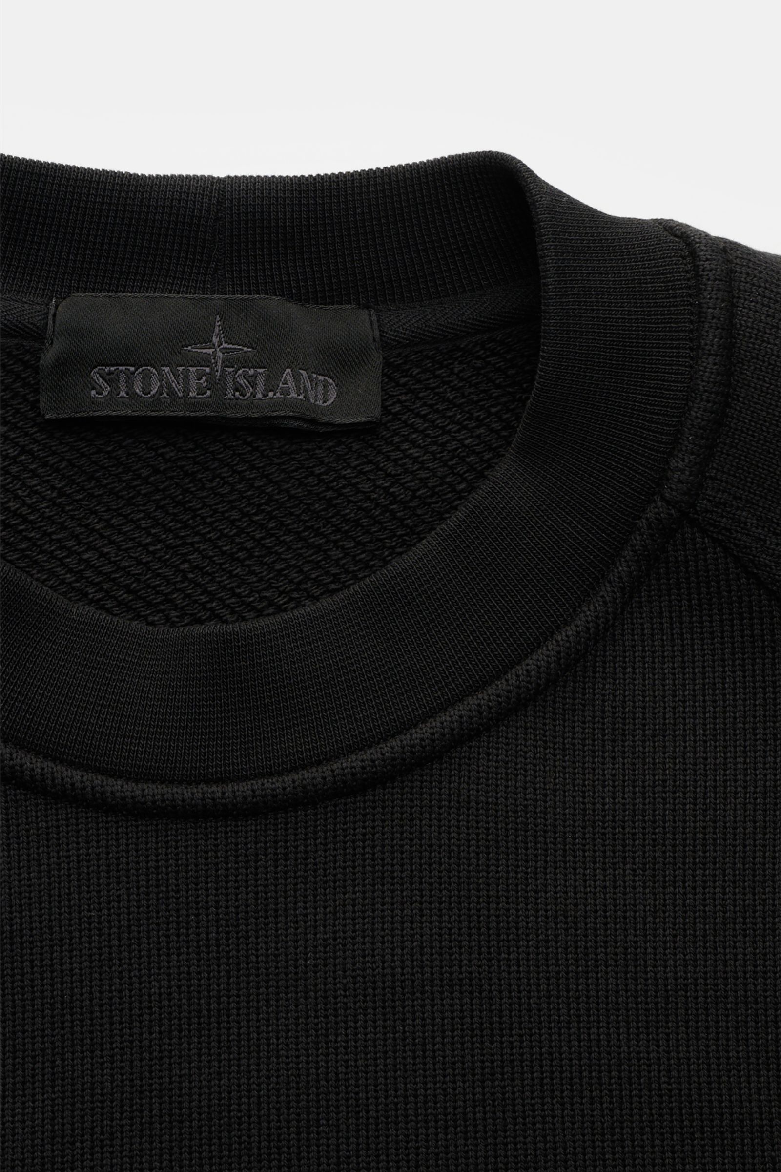Nahaufnahme des Stone Island Rundhals-Sweatshirt 'Ghost Piece' schwarz, reine Baumwolle, Regular Fit, Raglanärmel, tonales Badge, Rippbündchen.