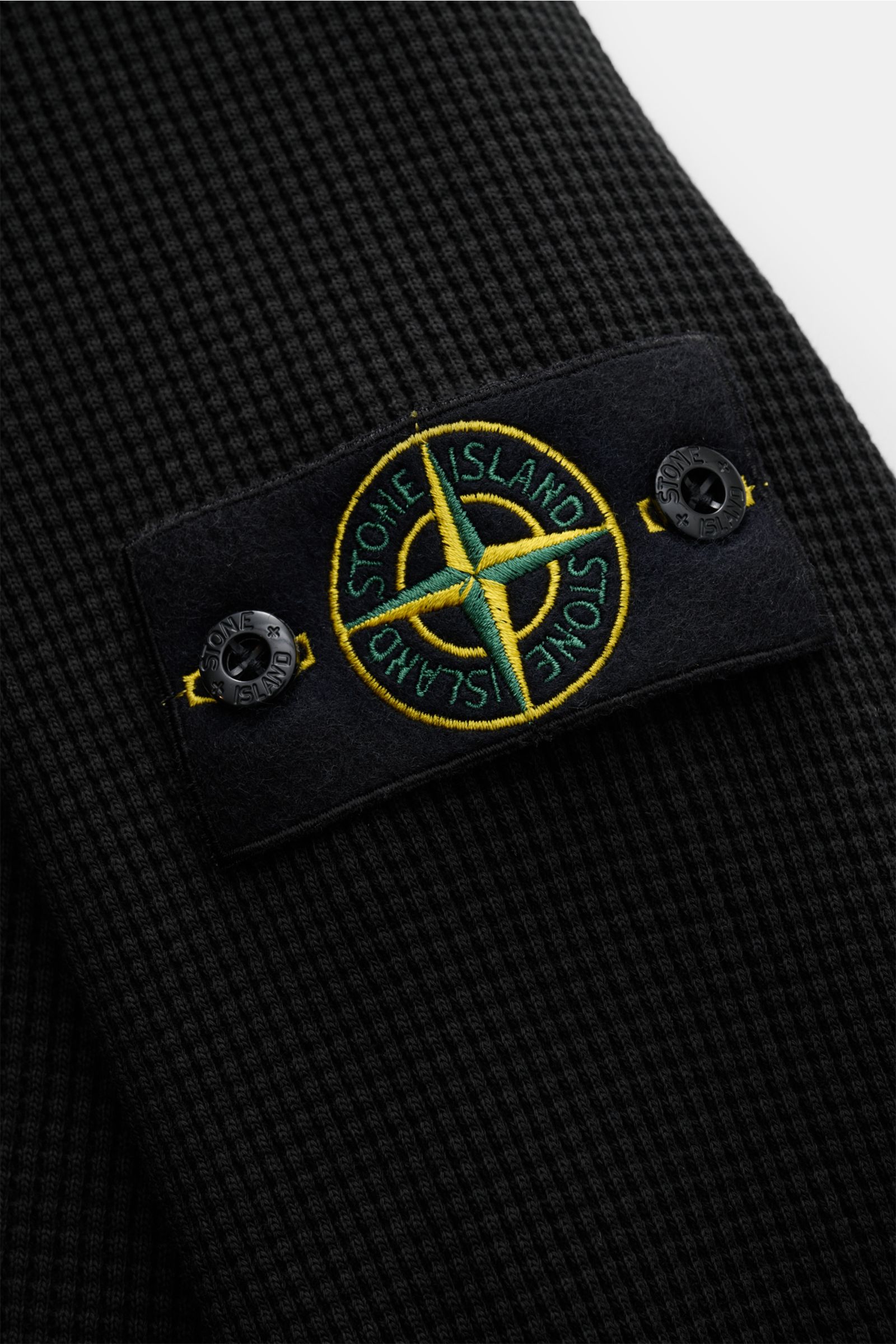 Stone Island Rundhalspullover 'Waffle' schwarz in Slim Fit, Waffelstrick aus Baumwolle mit Kompass-Badge am Oberarm, Detailansicht seitlich.