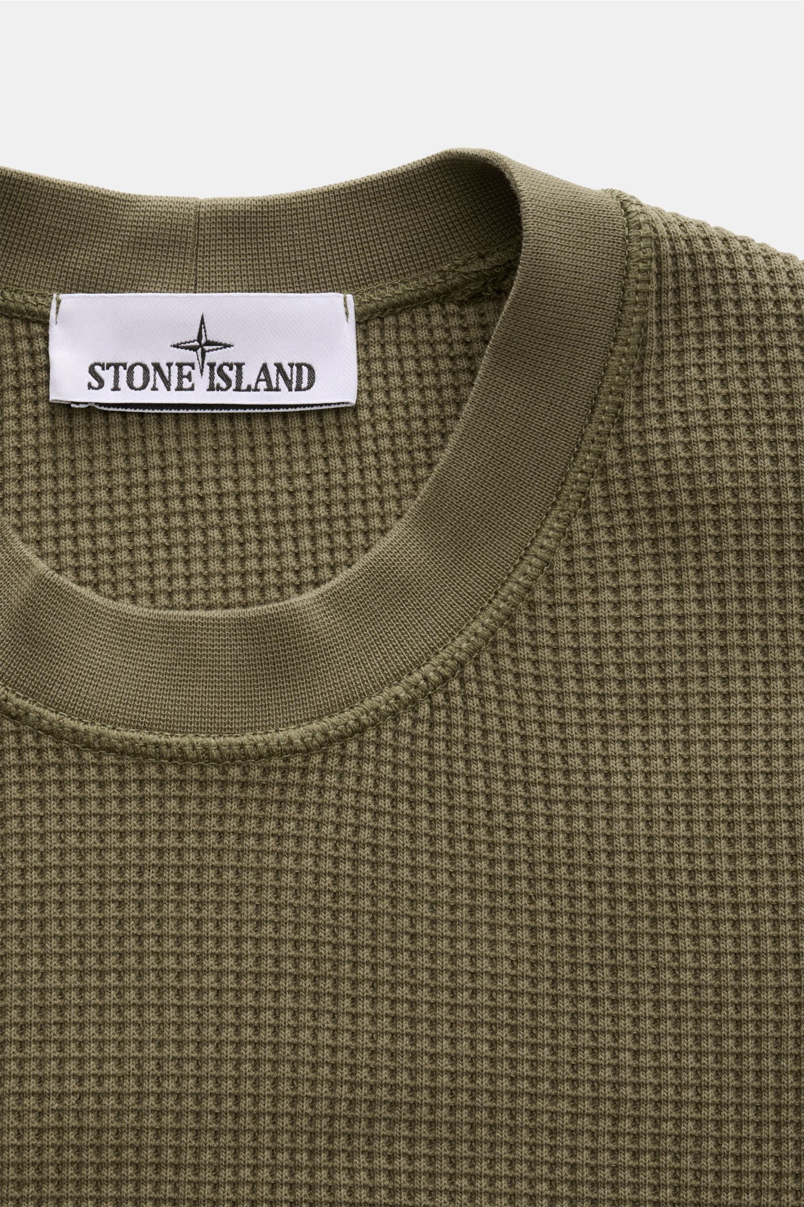 Stone Island Rundhalspullover 'Waffle' oliv shown from a close-up top front view, featuring waffle knit cotton fabric and ribbed crew neck. Basic Piece mit Twist: Dieser Pullover im Waffelstrick von STONE ISLAND wird zur idealen Grundlage moderner Frei