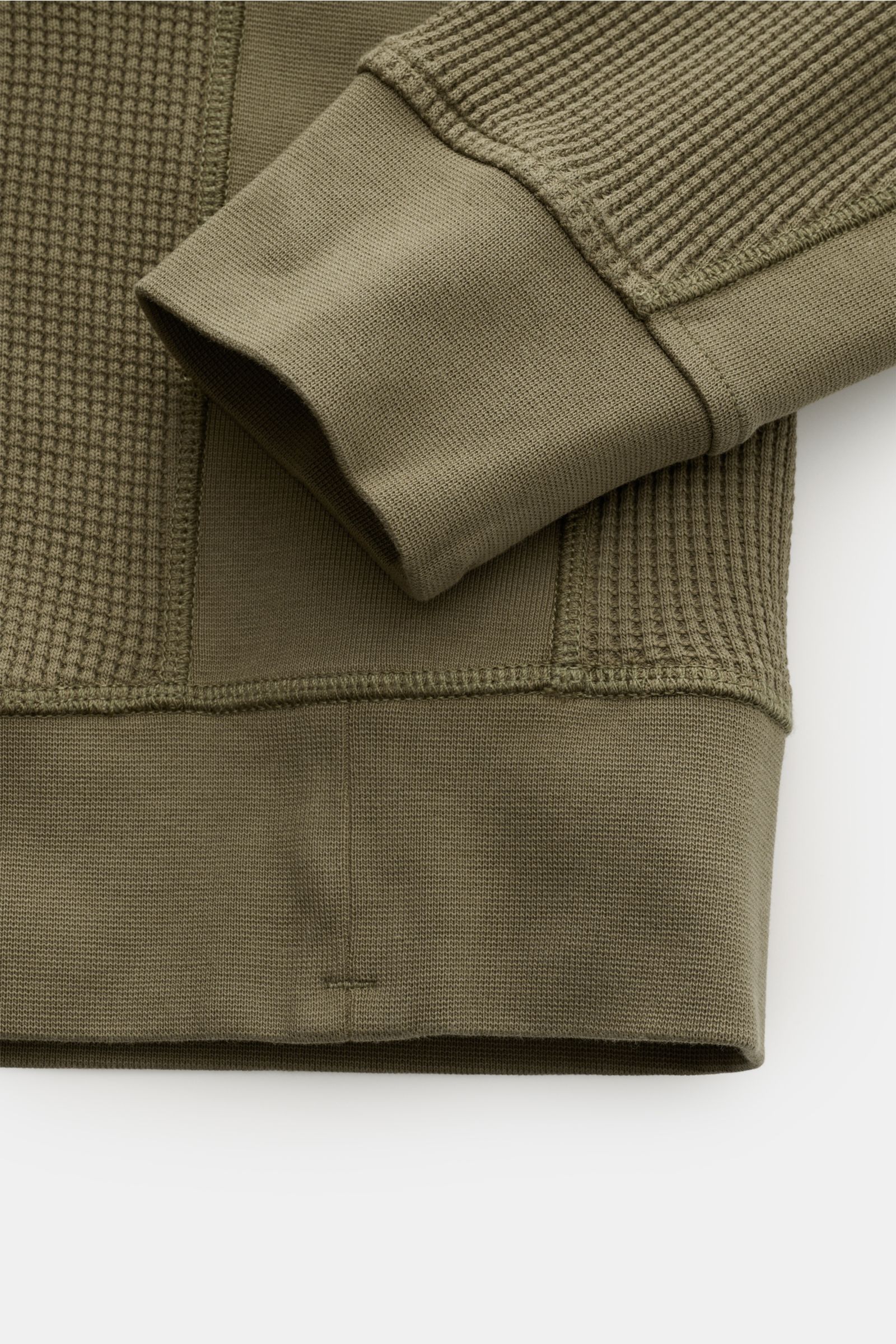 Stone Island Rundhalspullover 'Waffle' oliv close-up from above showing cuff and hem in olive green waffle knit and smooth cotton fabric with ribbed texture. 

Basic Piece mit Twist: Dieser Pullover im Waffelstrick von STONE ISLAND wird zur idealen Grundl