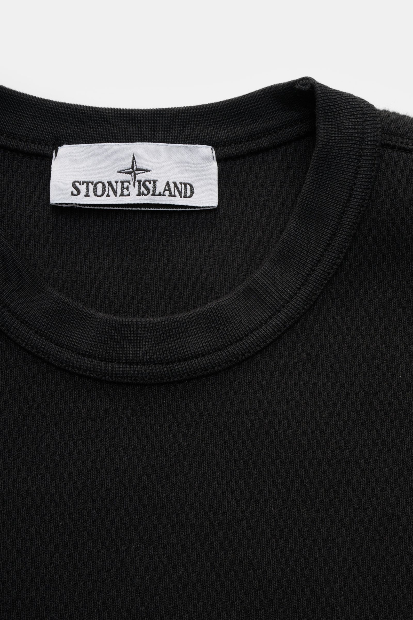 Stone Island Rundhalspullover schwarz, Nahaufnahme von oben, strukturierte Baumwolle, Rundhalsausschnitt, feines Strickbild, Overlock-Nähte sichtbar.