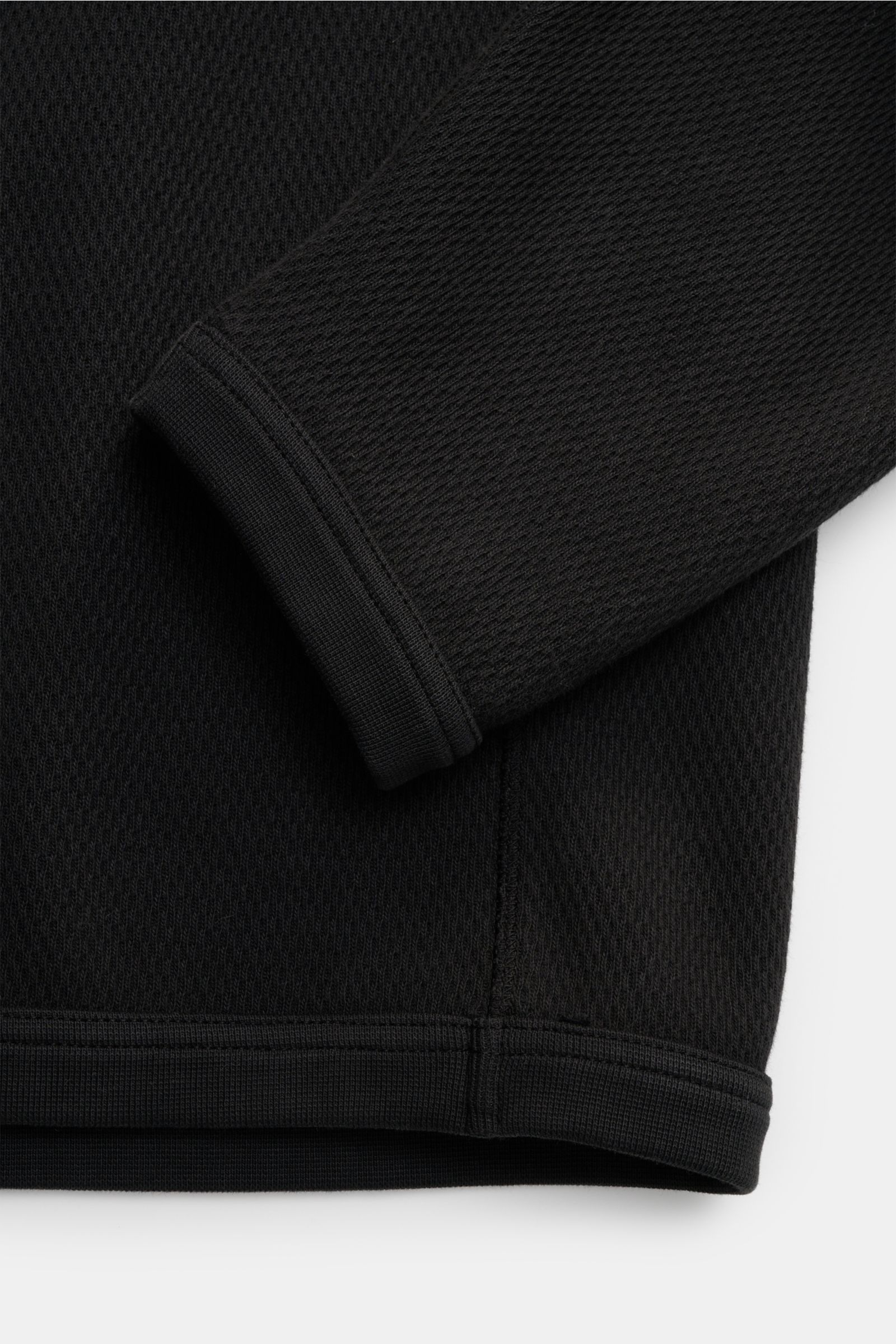 Stone Island Rundhalspullover schwarz in Nahaufnahme von unten, zeigt strukturierte Jersey-Qualität, Overlock-Nähte und elastische Bündchen.