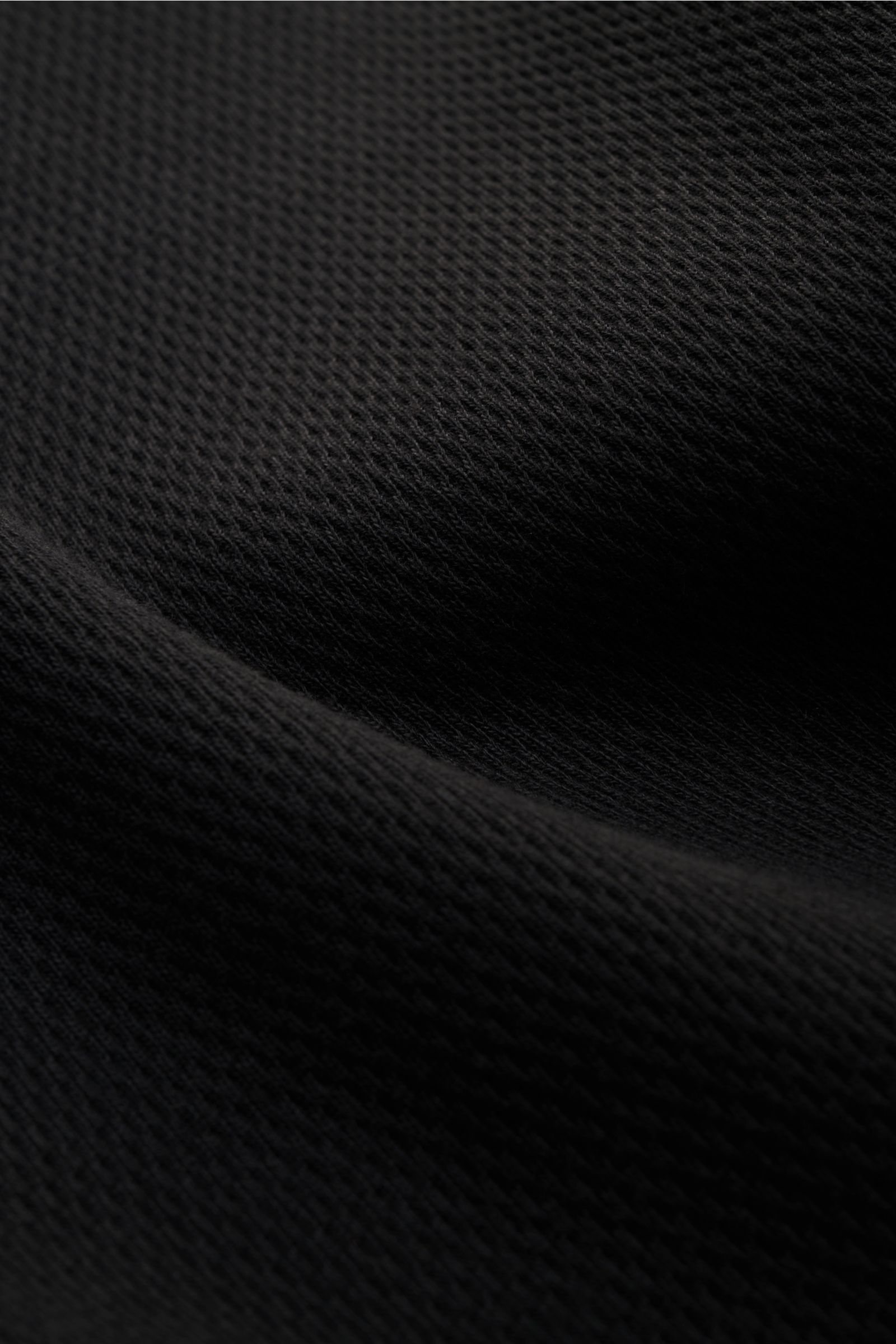 Nahaufnahme des Stone Island Rundhalspullover schwarz aus strukturierter Baumwolle mit feinem Strickbild, elastischen Bündchen und markantem Kompass-Badge.