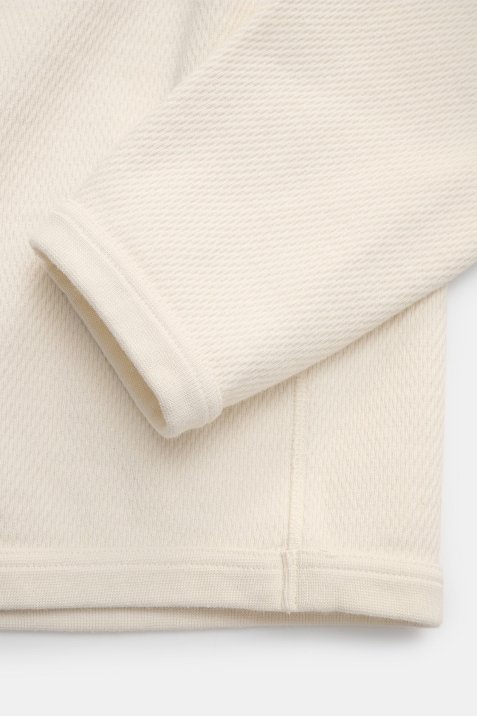 Detailaufnahme des Stone Island Rundhalspullover creme von schräg oben, zeigt strukturierte Baumwolle, markante Overlock-Nähte und elastische Bündchen.