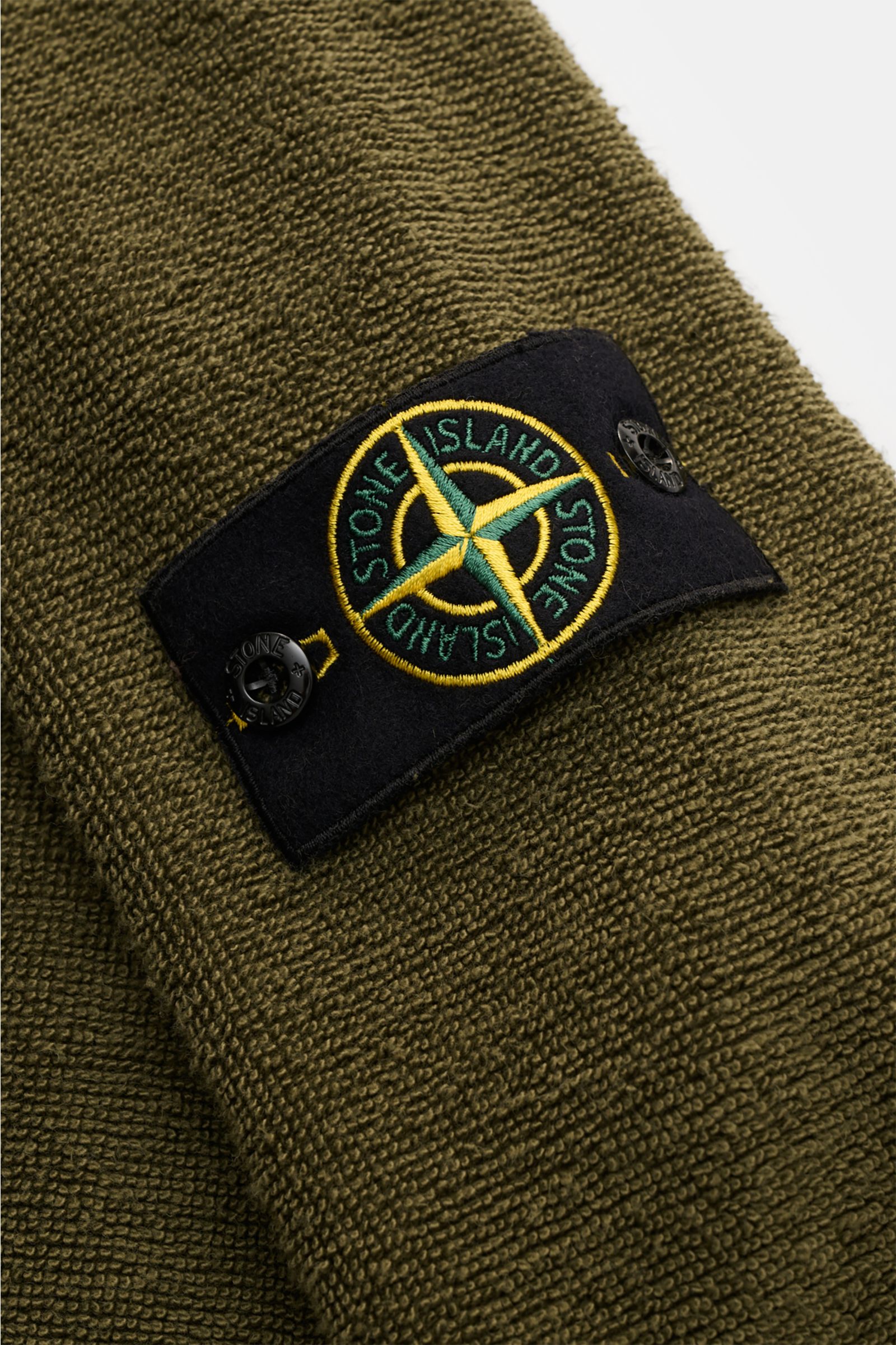 Nahaufnahme des Stone Island Frottee-Rundhals-Sweatshirts oliv, Perspektive von oben auf das schwere Baumwolle-Microfaser-Material mit markantem Kompass-Badge.