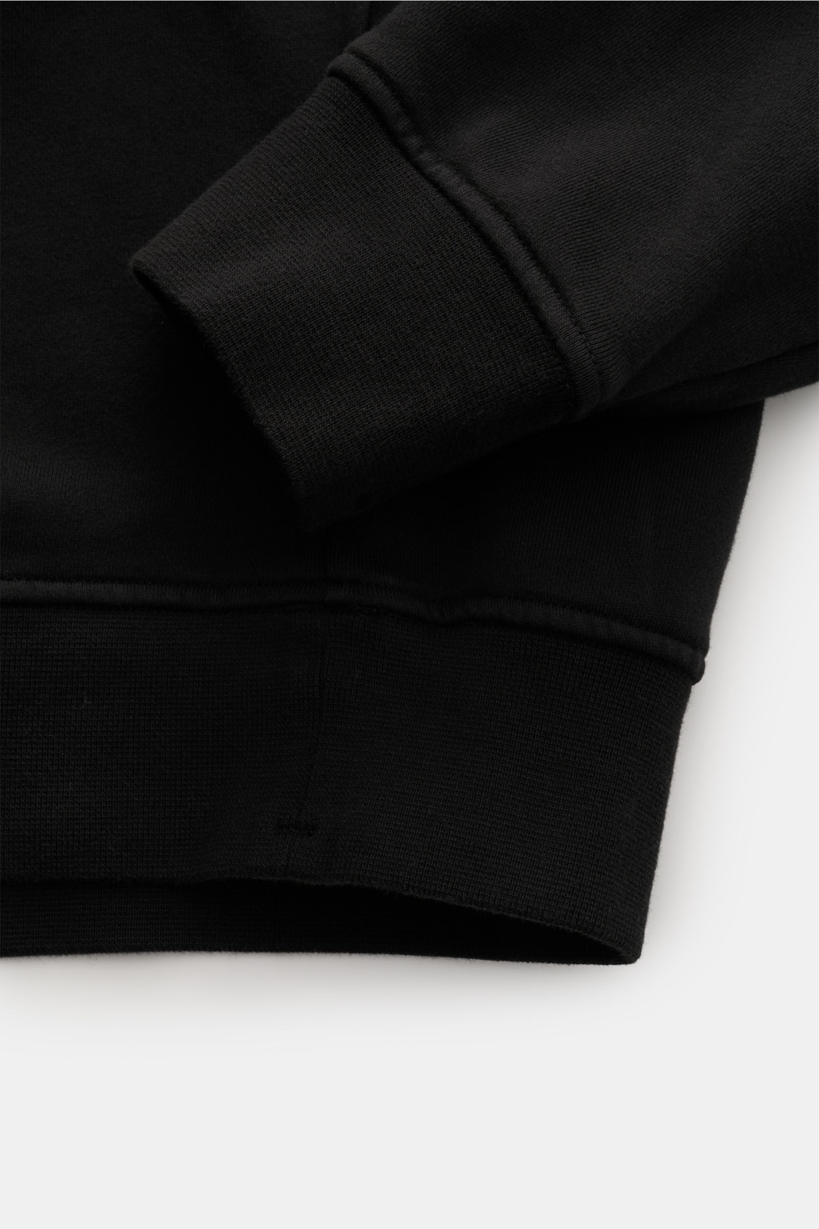 Close-up view of cuff and hem of Stone Island Rundhals-Sweatshirt 'Seasonal Pocket' schwarz, showing black cotton fabric and ribbed details.

Description: Zeitloses Basic Piece: Das sportive Sweatshirt von STONE ISLAND wird zur idealen Grundlage legere