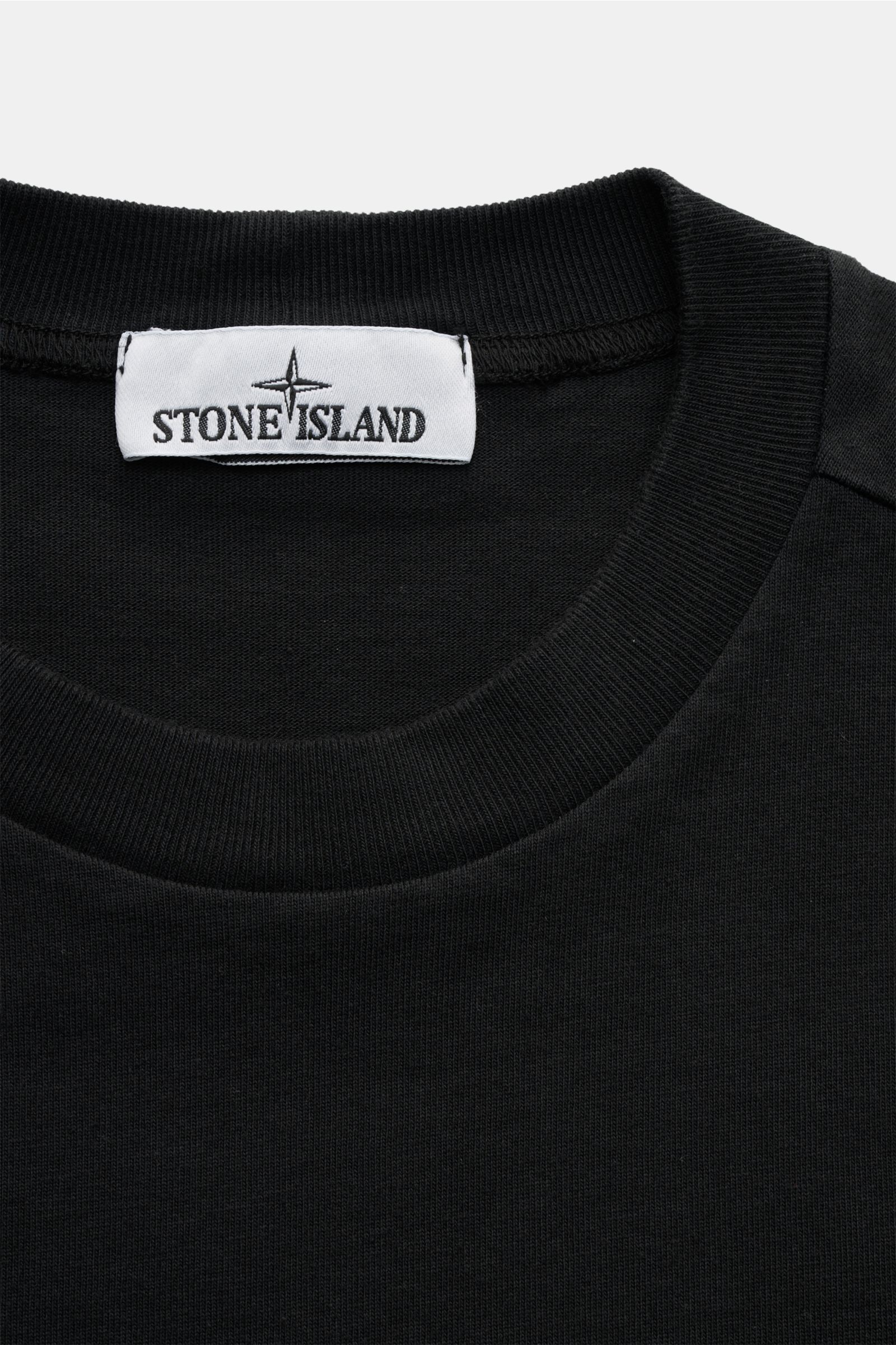 Close-up front view of Stone Island Long sleeve black crew neck sweatshirt showing ribbed collar and label.

With this crew neck long sleeve in heavy cotton jersey with compass badge on the sleeve, STONE ISLAND brings us a comfortable basic for cool ca