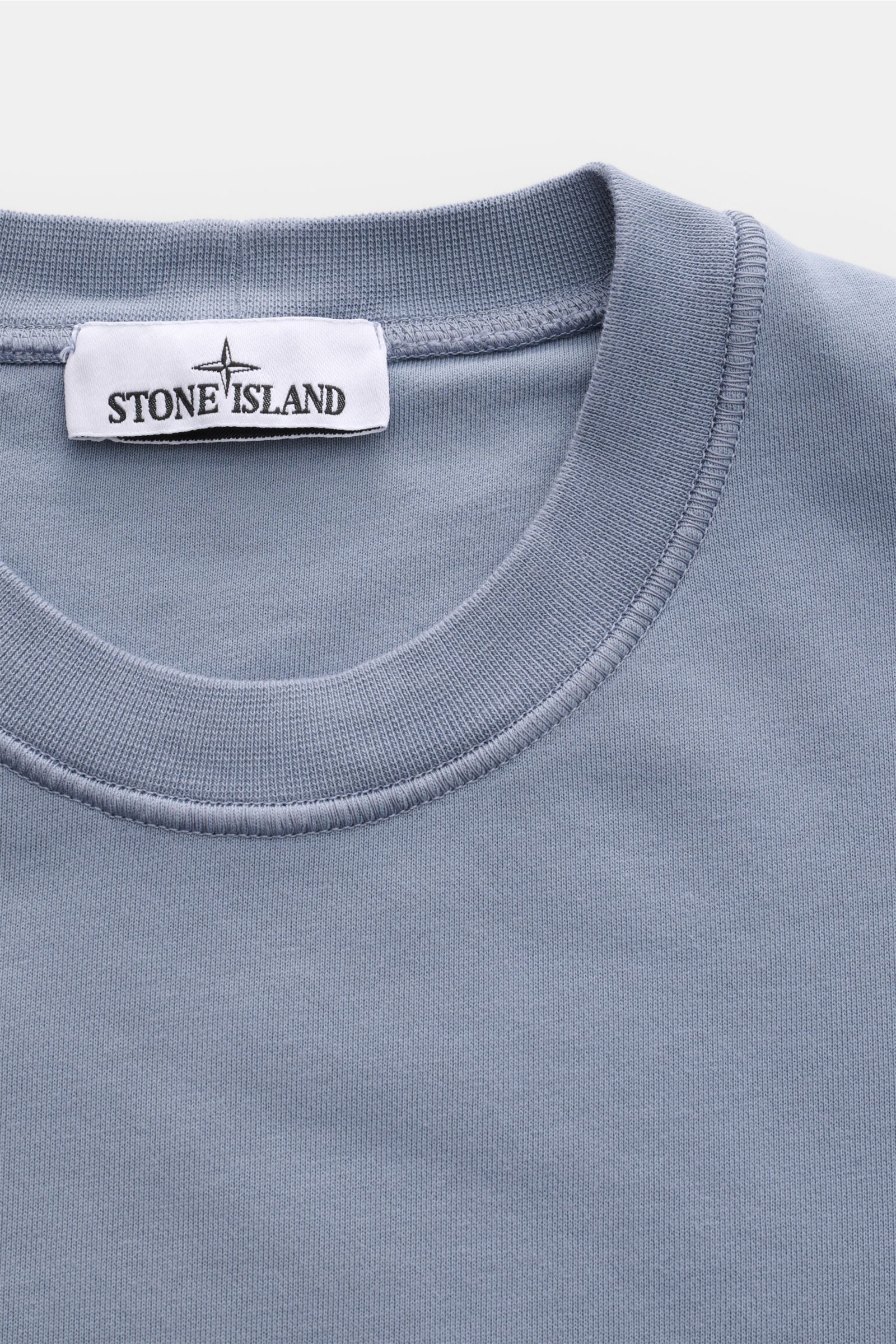 Stone Island Rundhals-Sweatshirt 'Basic Sweat' rauchblau, Nahaufnahme von Kragen und Label, weicher Baumwollstoff, Regular Fit, Rippbündchen, Kompass-Badge am Oberarm.