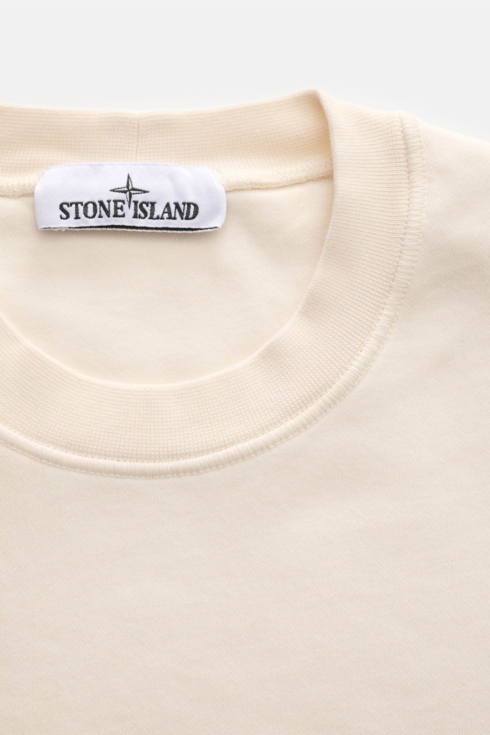 Stone Island Rundhals-Sweatshirt 'Basic Sweat' creme, Nahaufnahme von oben, weicher Baumwollstoff, Rippbündchen, Kompass-Badge am Oberarm, Regular Fit.