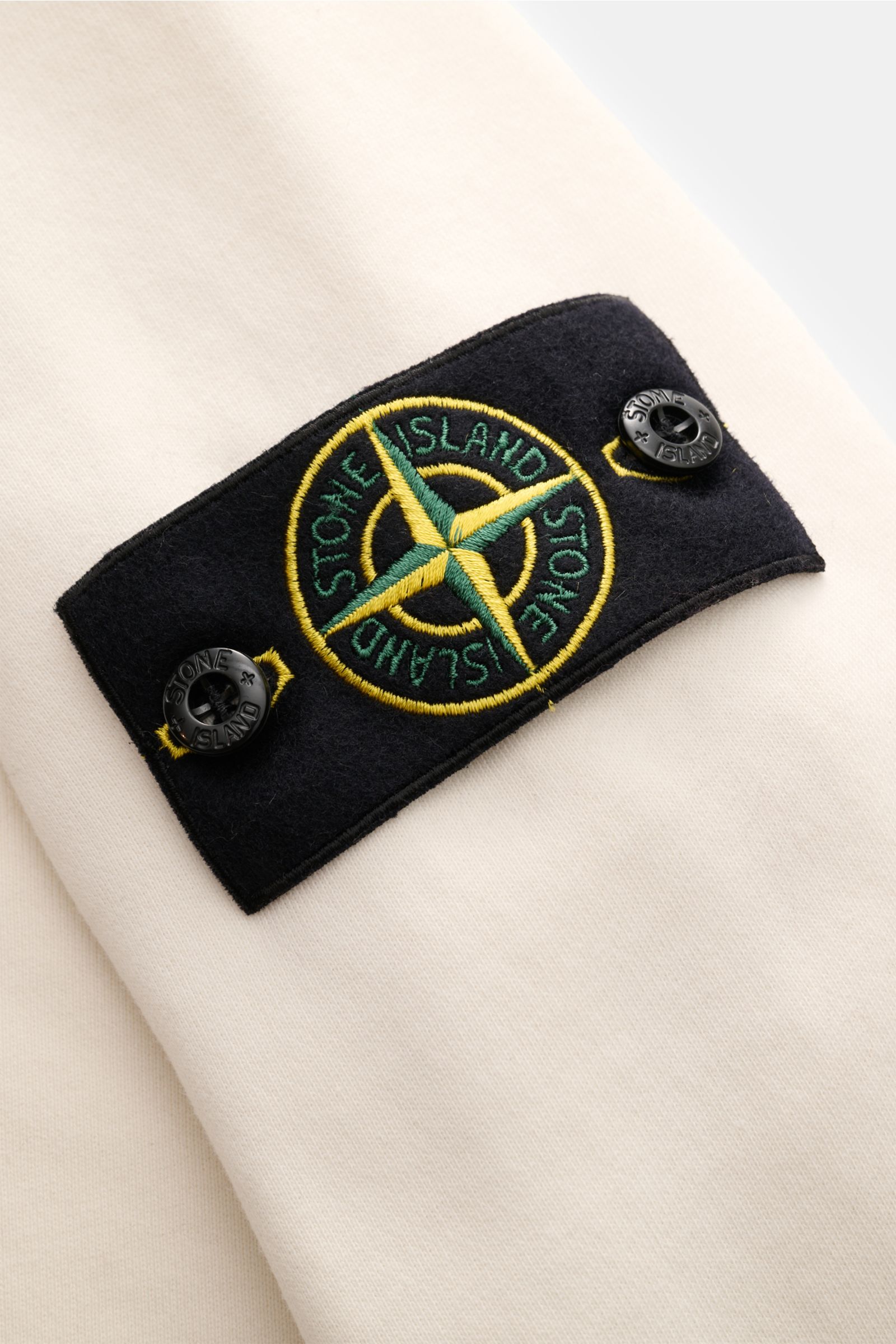 Stone Island Rundhals-Sweatshirt 'Basic Sweat' creme, Nahaufnahme des Kompass-Badges am Oberarm, weicher Baumwollstoff.