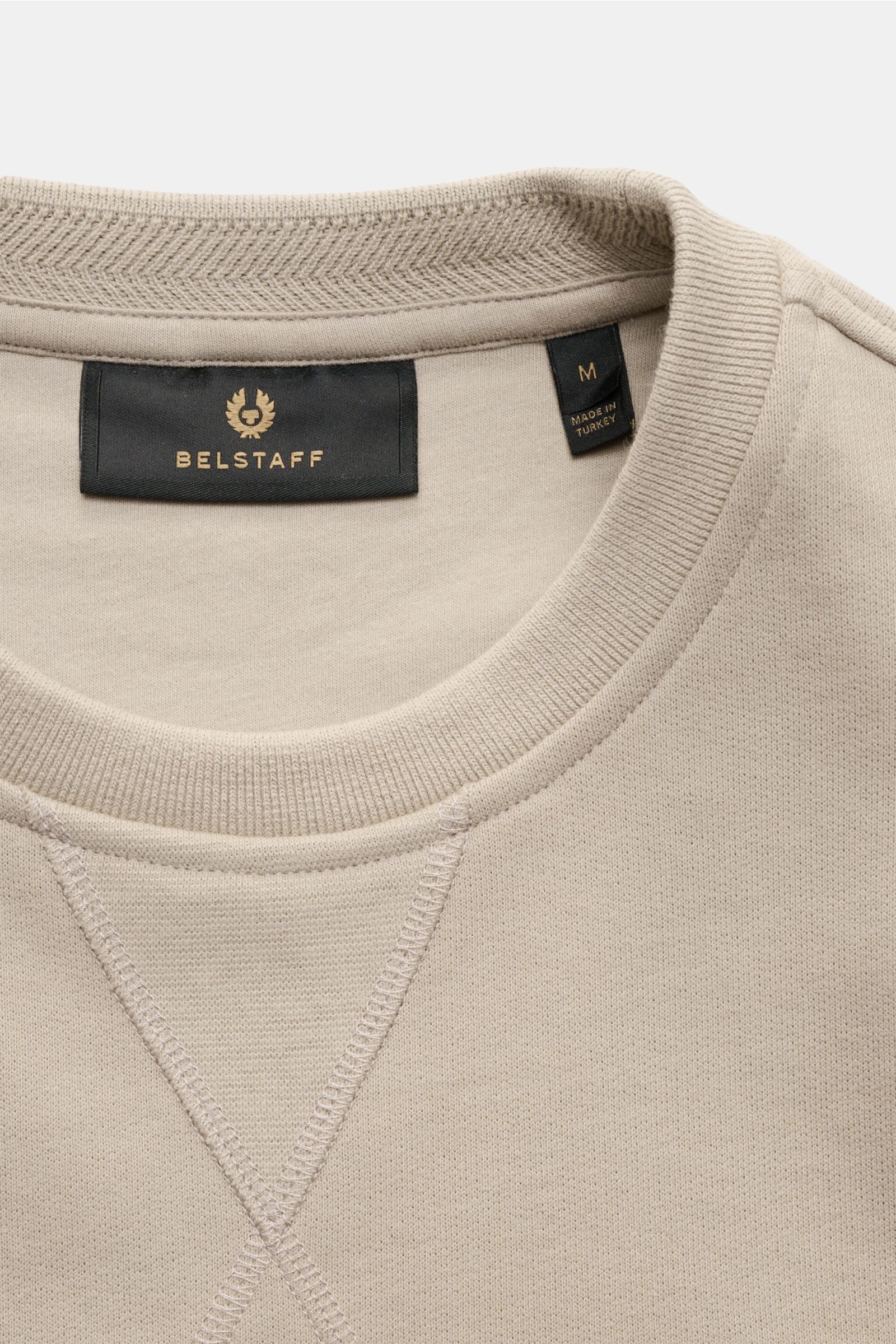 Belstaff Sweatshirt beige shown from a close-up top-front perspective, featuring a crew neck with V-stitch and a tonal woven label. This sweatshirt by BELSTAFF creates modern accents with artistic decorative stitching, the characteristic V-stitch and a