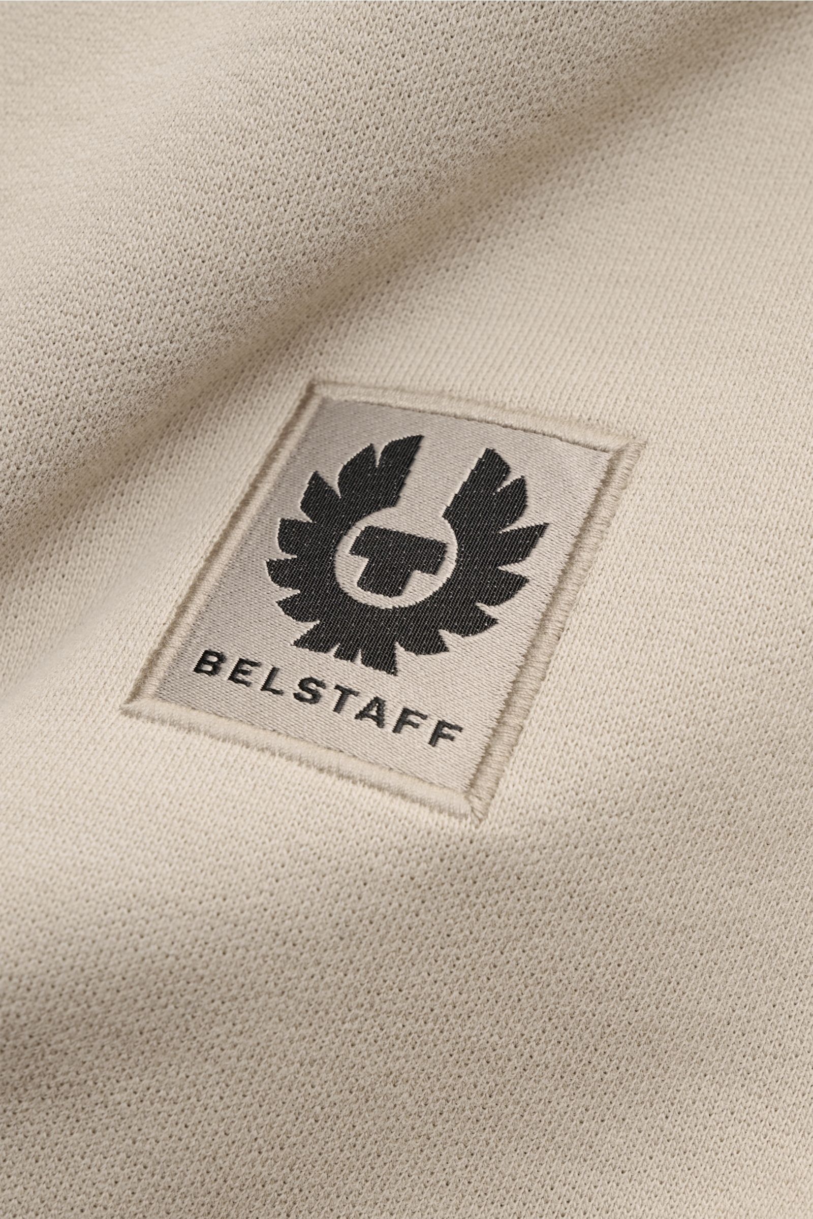 Nahaufnahme des tonalen BELSTAFF-Weblabels auf dem weichen, beigen Belstaff Sweatshirt mit V-Stitch und Slim Fit aus reiner Baumwolle.