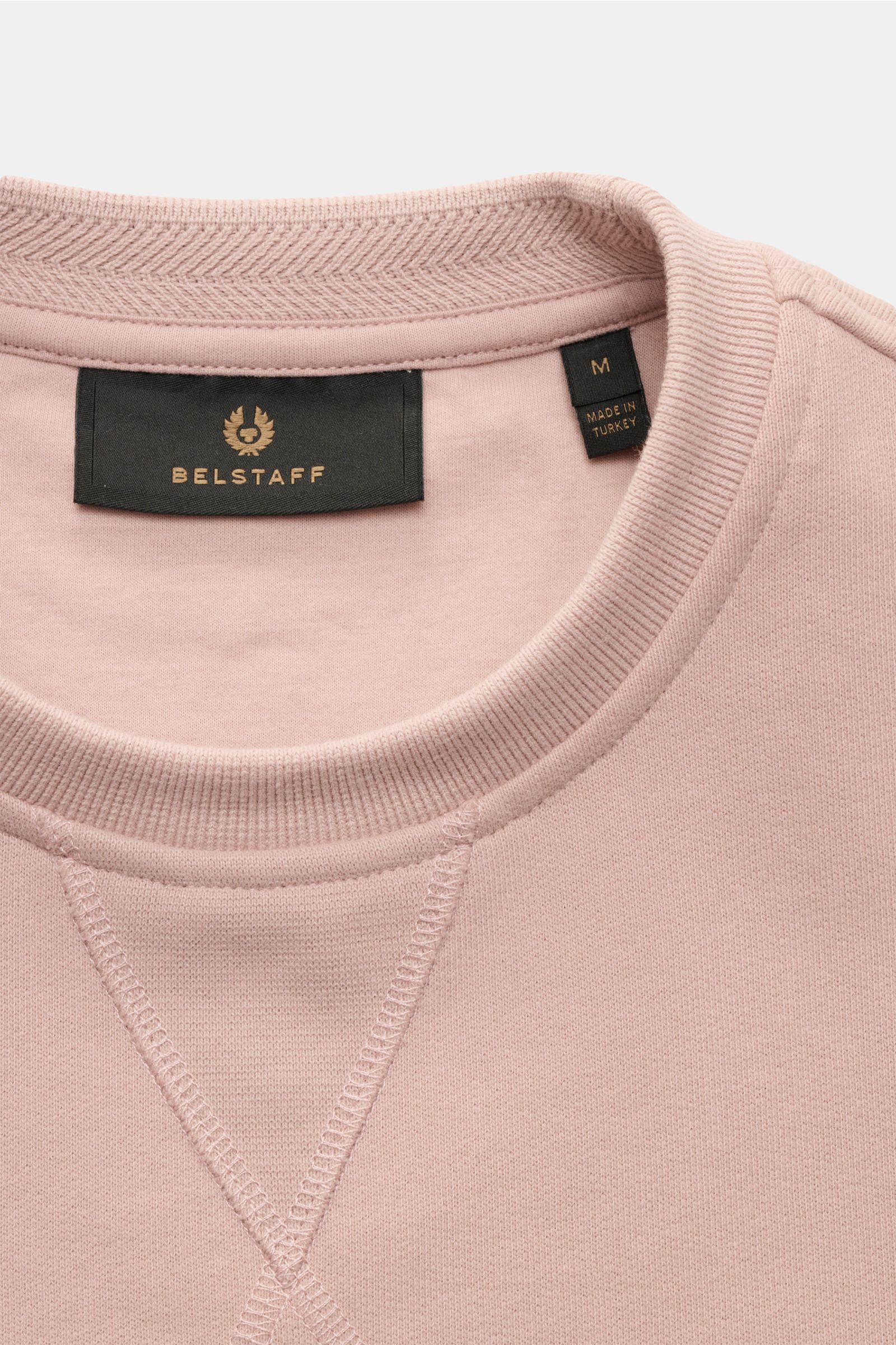 Close-up front top view of Belstaff Sweatshirt antique pink showing crew neck with V stitch, tonal woven label, and soft cotton fabric.

This sweatshirt by BELSTAFF creates modern accents with artistic decorative stitching, the characteristic V-stitch 