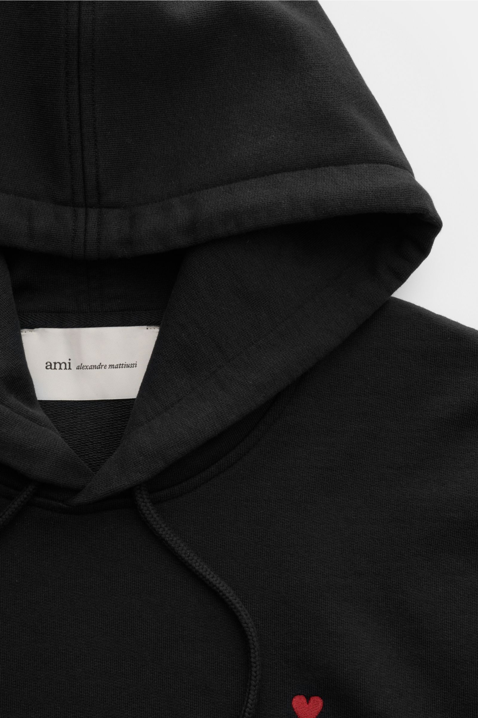 Ami Paris Kapuzenpullover schwarz, Nahaufnahme von oben, aus reiner Baumwolle, Regular Fit, Kapuze mit Tunnelzug, rotes Logo-Stitching, Kängurutasche, weicher Griff.