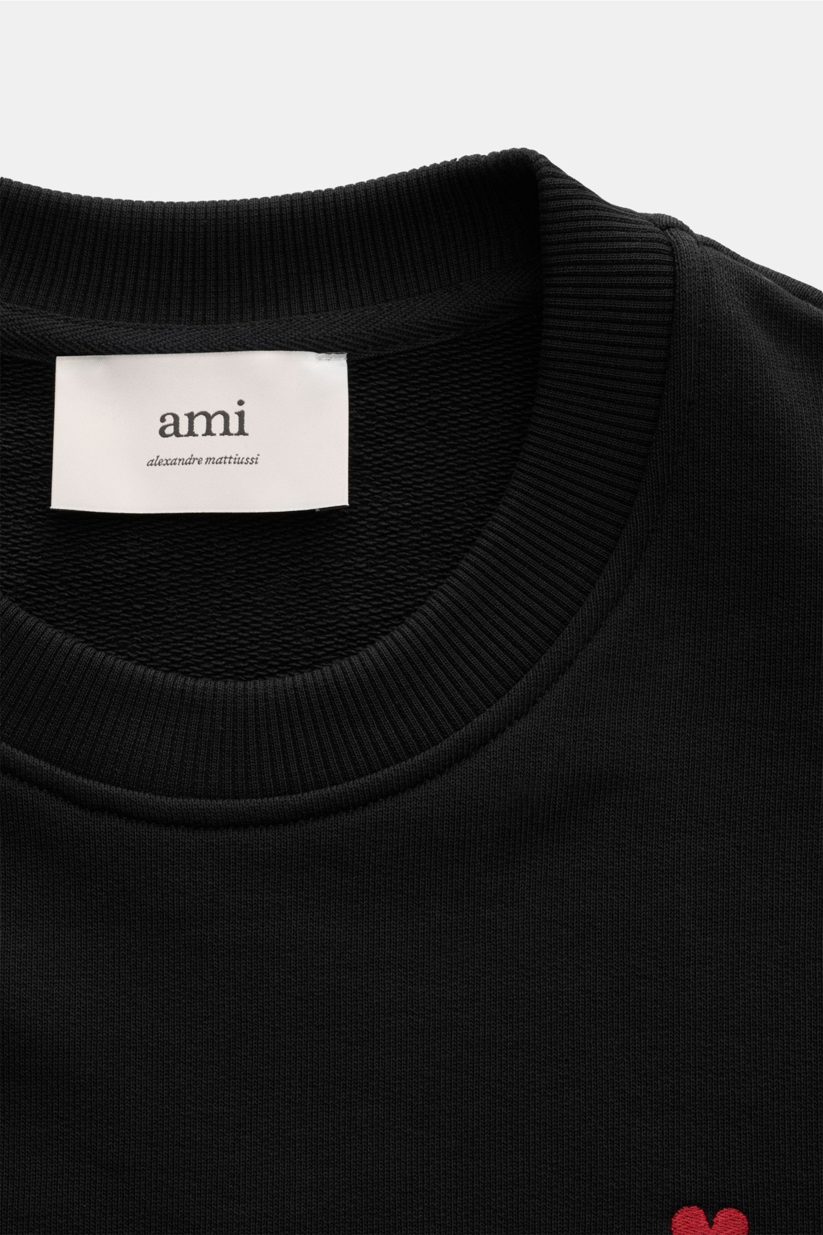 Ami Paris Rundhals-Sweatshirt schwarz shown from a close-up top-down angle, focusing on the ribbed neckline, label, and part of the chest logo. 

Komfortables Basic: Das AMI PARIS Sweatshirt aus reiner Baumwolle ist der ideale Begleiter für sportive Lo