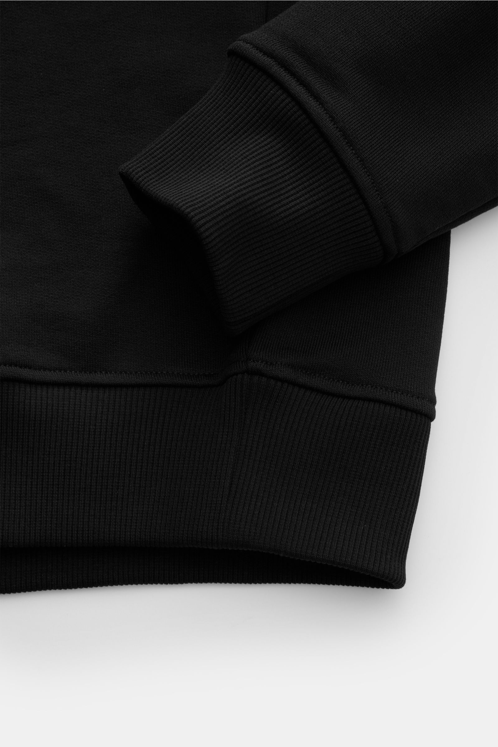 Close-up of the ribbed cuff and hem of the Ami Paris Rundhals-Sweatshirt schwarz, showing soft cotton fabric from a side angle.

Komfortables Basic: Das AMI PARIS Sweatshirt aus reiner Baumwolle ist der ideale Begleiter für sportive Looks.

