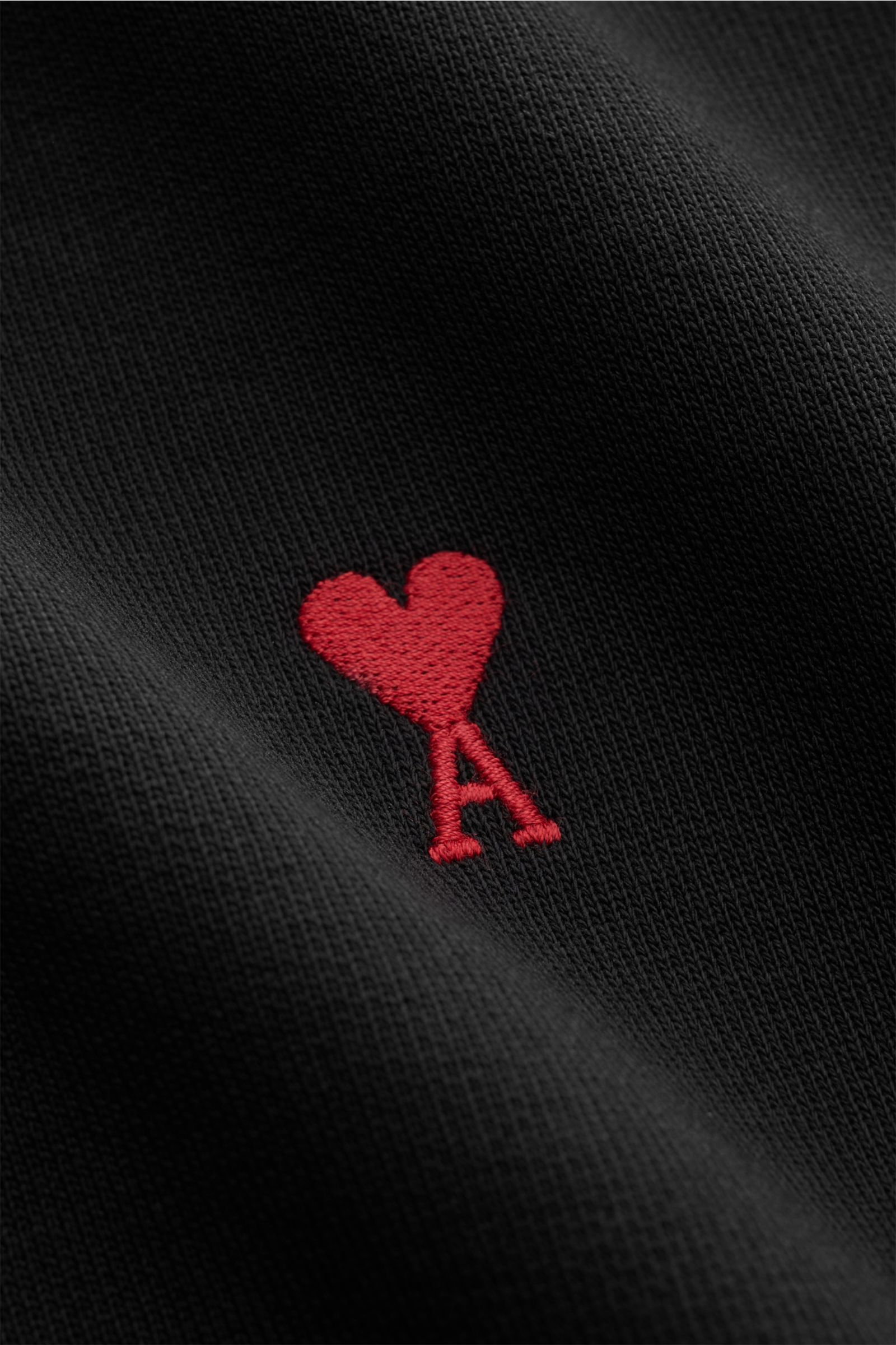 Close-up front view of Ami Paris Rundhals-Sweatshirt schwarz showing red heart and A logo stitching on black cotton fabric.

Komfortables Basic: Das AMI PARIS Sweatshirt aus reiner Baumwolle ist der ideale Begleiter für sportive Looks.

Swe