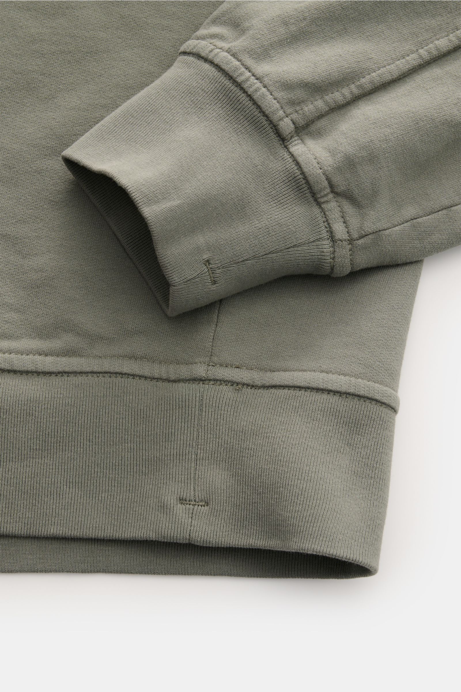 Close-up front view of C.P. Company Sweatshirt salbei showing the ribbed cuff and hem in soft, garment-dyed pure cotton with slim fit and lens detail. 