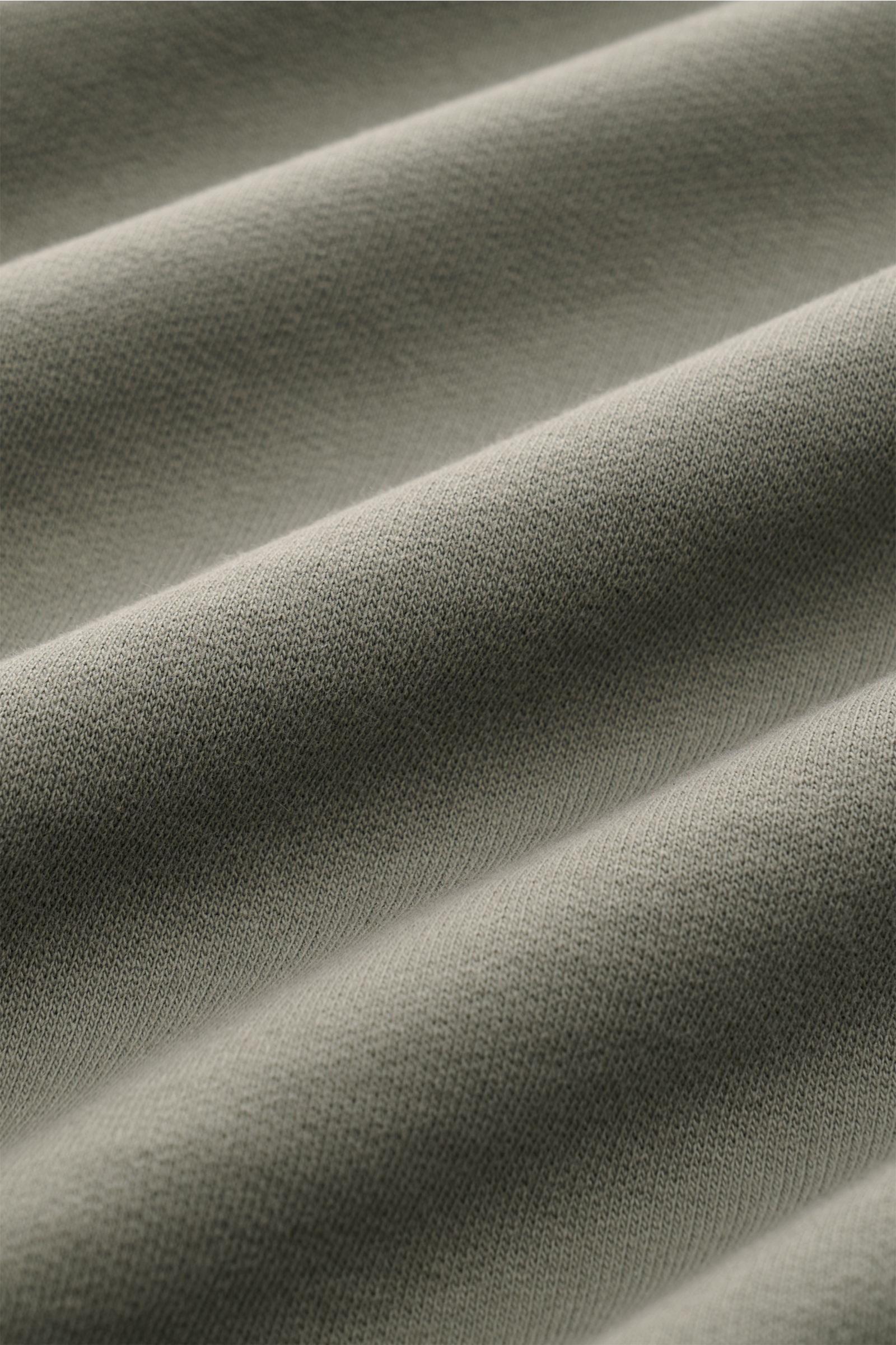 Close-up front-angle view of fabric texture in a garment dyed C.P. Company Sweatshirt salbei, showing soft, lightweight cotton knit with fine ribbing and smooth folds. 