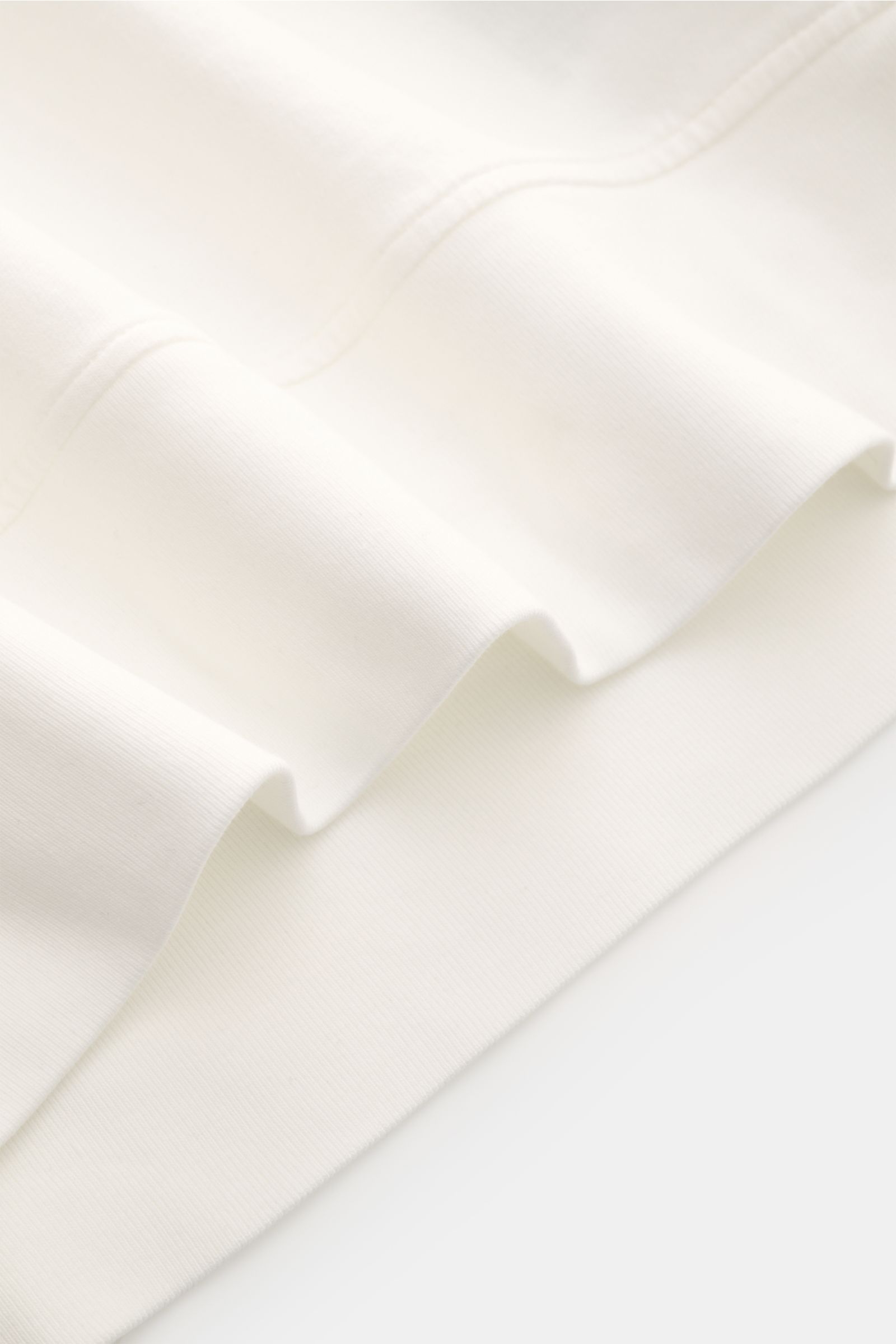 Close-up front view of C.P. Company Sweat-Troyer offwhite showing soft, lightweight cotton fabric with garment dyed finish and ribbed cuffs, highlighting sporty design and iconic lens detail. Schon auf den ersten Blick spürt man die sportive DNA: Das inno