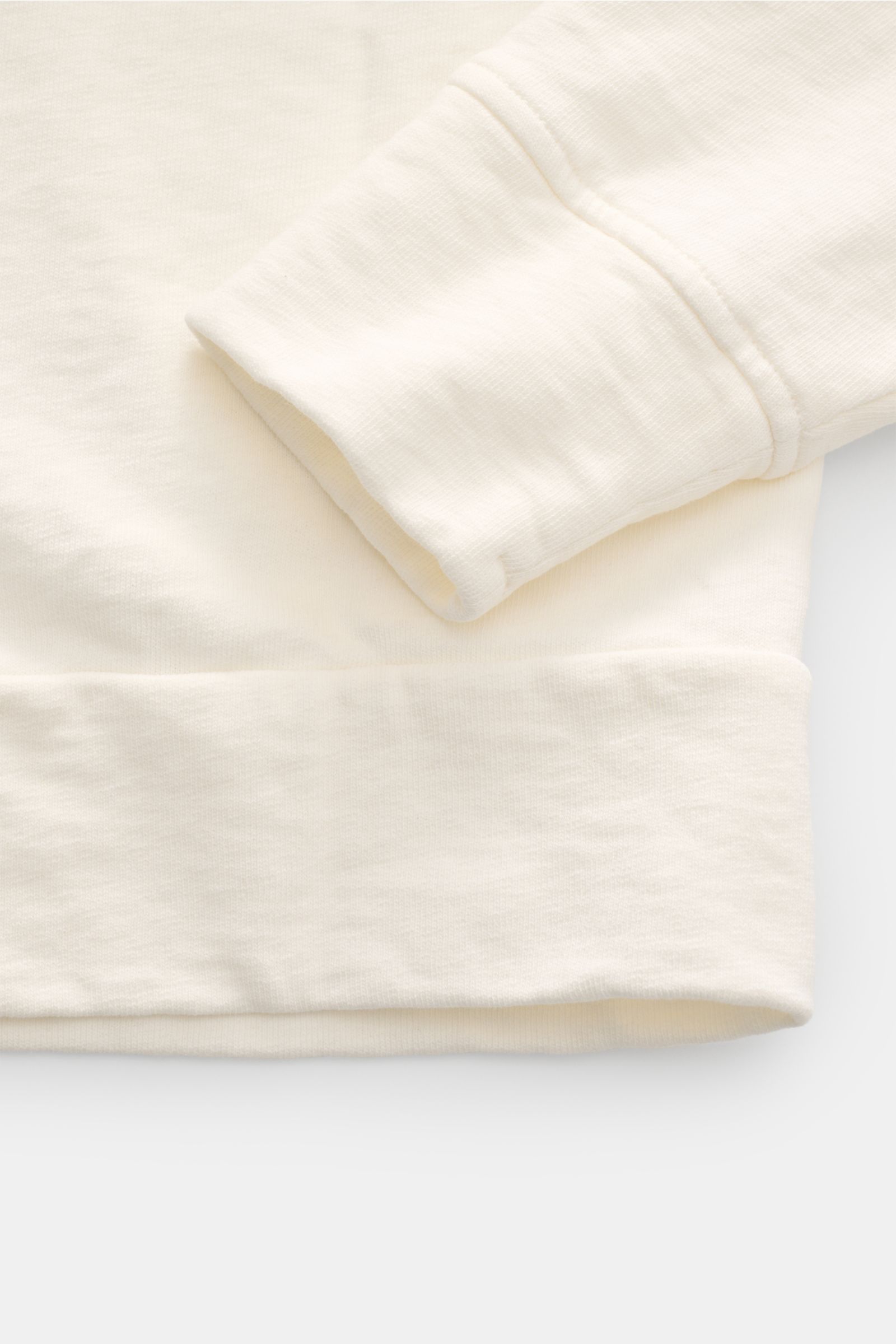 Nahaufnahme des C.P. Company Rundhals-Sweatshirt creme, seitliche Perspektive auf Ärmel und Saum mit Nahtdetails und Rippbündchen.