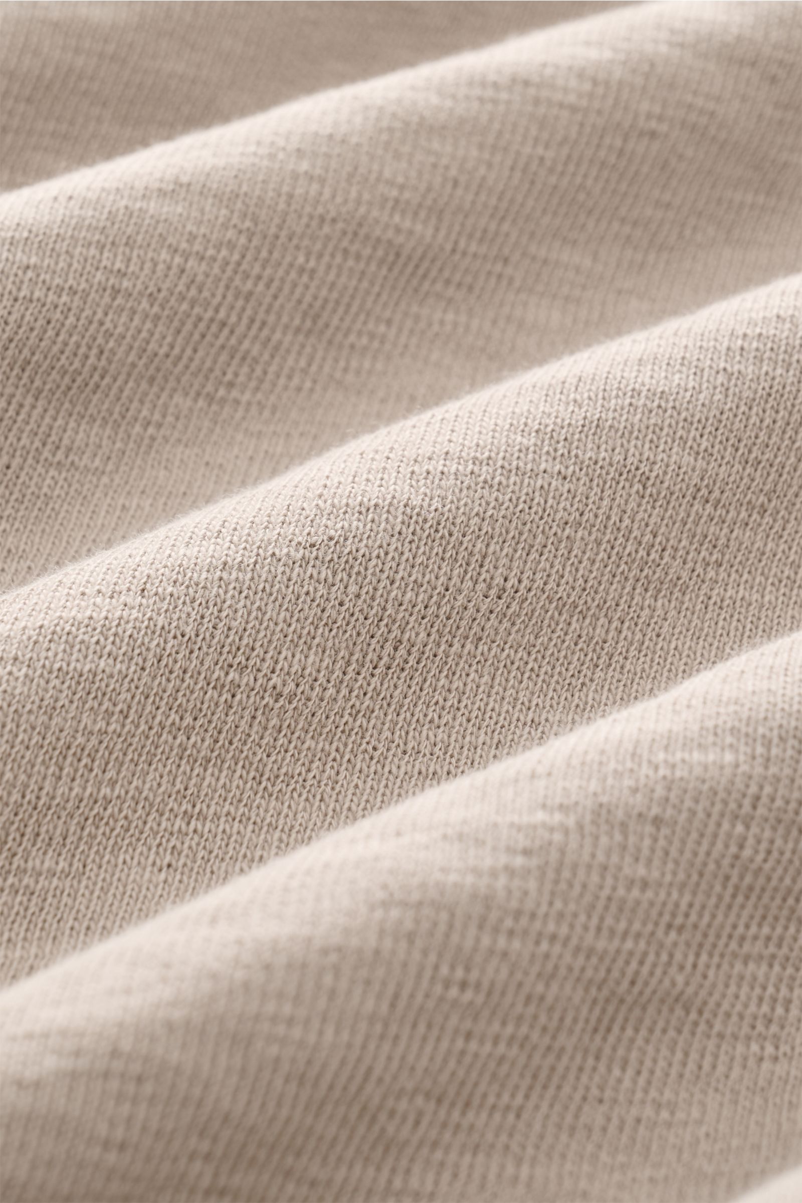 Close-up view of the beige fabric texture of the C.P. Company Rundhals-Sweatshirt beige, showing its typical garment-dyed washed design and fine cotton knit with soft ribbed details. 