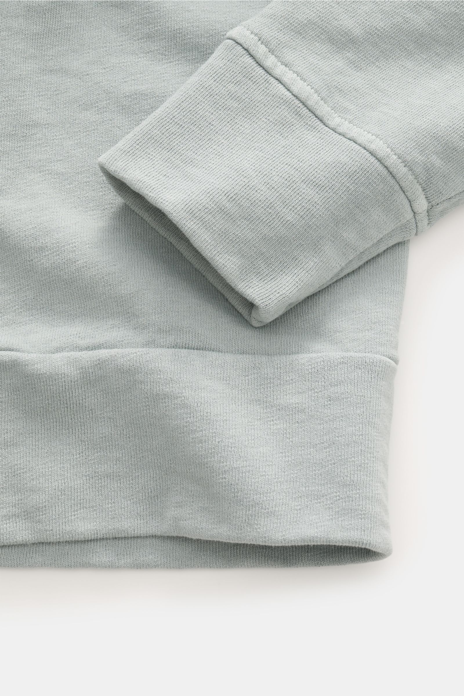 C.P. Company Crew neck sweatshirt grey-green shown in close-up from above, highlighting the ribbed cuff and hem, made of pure cotton with garment-dyed washed design, lightweight fabric, and signature casual look with flexible ribbed bands. 