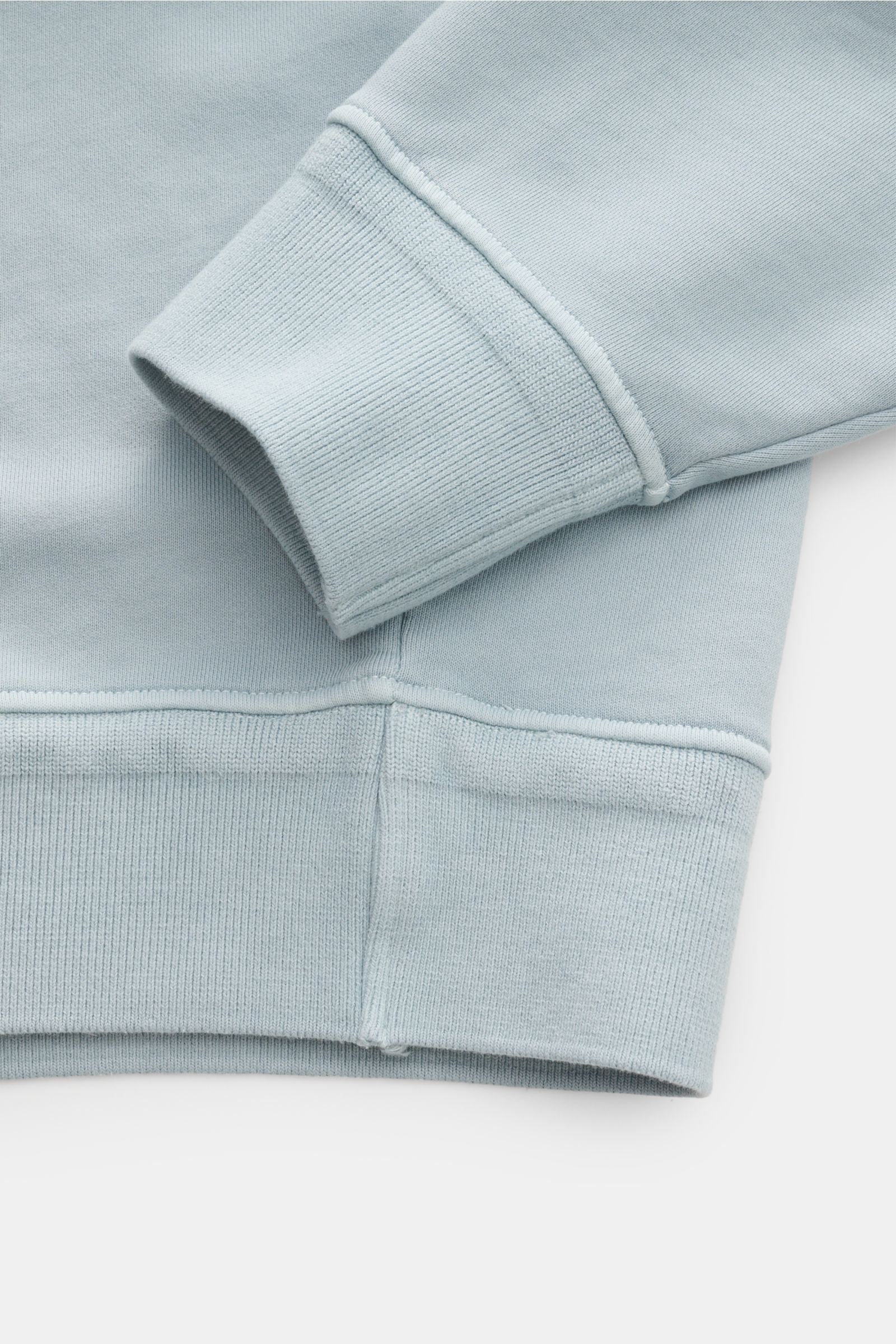 Nahaufnahme des Ärmels und Saums vom C.P. Company Sweatshirt rauchblau, aus reiner Baumwolle mit weichen, flexiblen Rippbündchen.