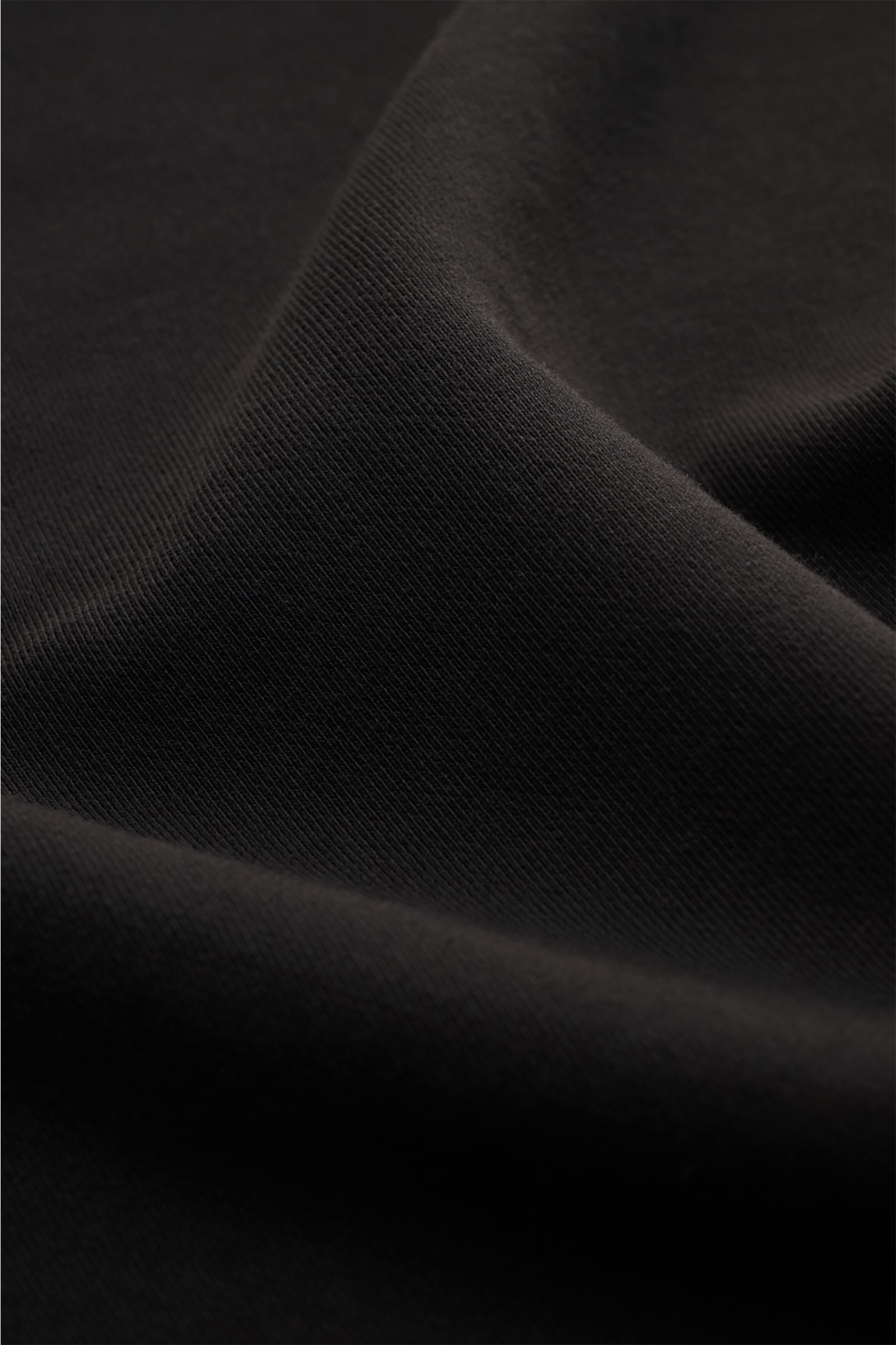 Nahaufnahme des schwarzen C.P. Company Sweatshirts mit feiner Baumwollstruktur, fotografiert aus schräger Perspektive.