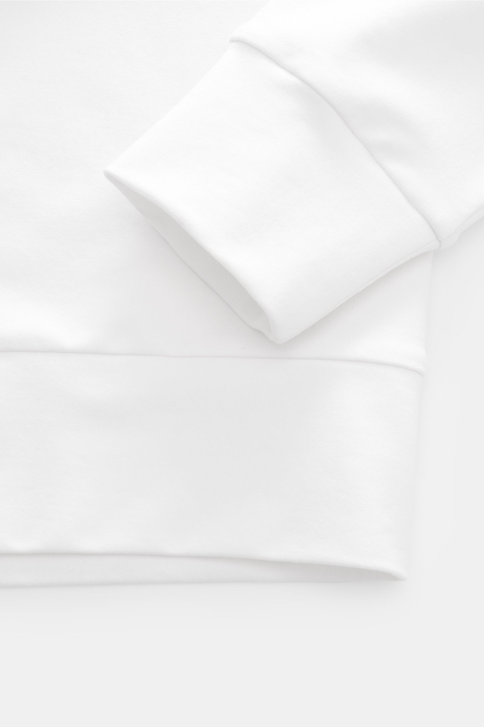 Close-up image from above showing the cuff and hem details of the Stefan Brandt Sweat-Troyer 'Joar' weiß in soft white fabric. Luxus, den man spürt: Selbst ein Basic wie der Sweat-Troyer 'Joar' wird bei 