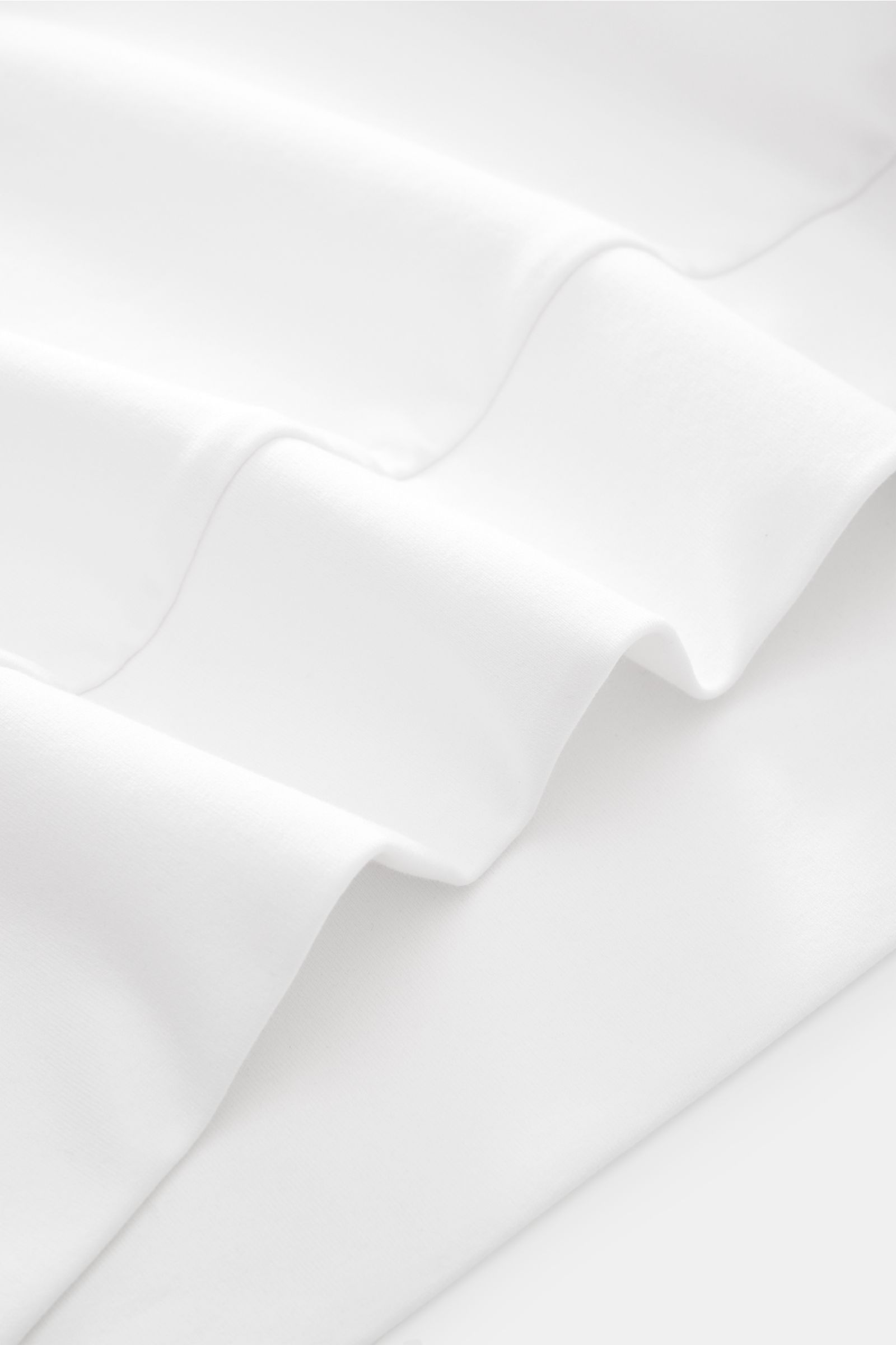 Close-up from above of the soft white fabric of the Stefan Brandt Sweat-Troyer 'Joar' weiß, showcasing its smooth, lightweight Pima cotton texture. Luxus, den man spürt: Selbst ein Basic wie der Sweat-Troyer 'Joar' wird bei 