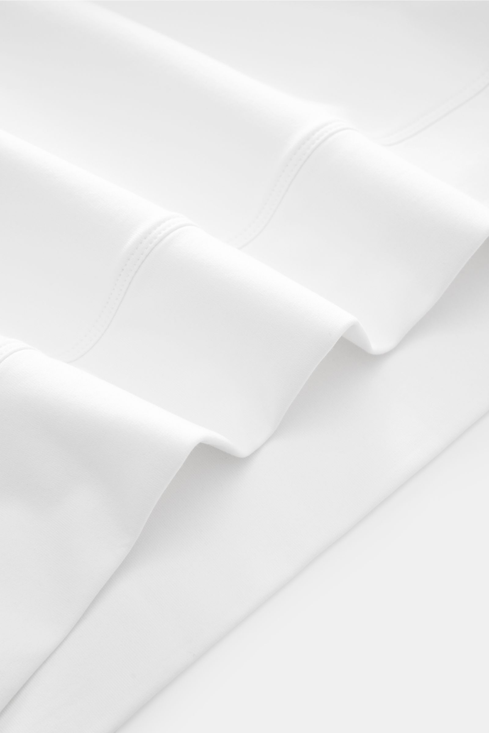 Close-up image of folded Stefan Brandt Sweatshirt 'Edwin' weiß fabric, showing soft, smooth white Pima cotton with fine stitching. Luxus, den man spürt: Selbst ein Basic wie das Sweatshirt 'Edwin' wird bei STEFAN BRANDT zum Inbegriff von Komfort und Quali
