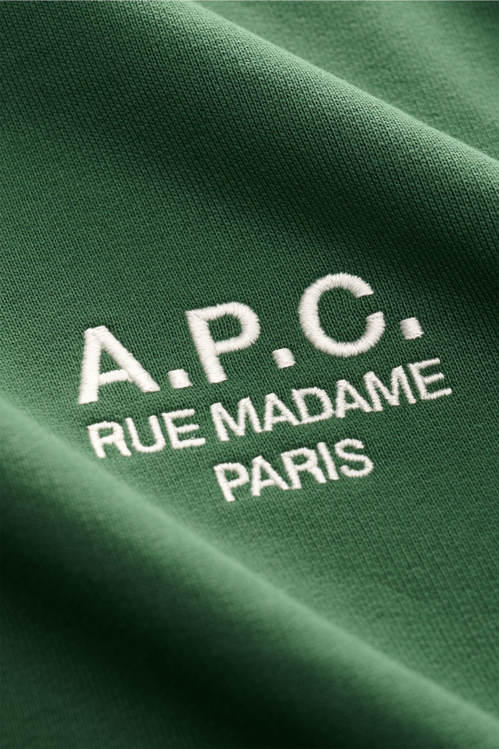 Nahaufnahme des dunkelgrünen A.P.C. Rundhals-Sweatshirts 'Standard Rue Madame' mit weißem Sticklogo, Detailansicht der Baumwollstruktur, weich und elastisch.