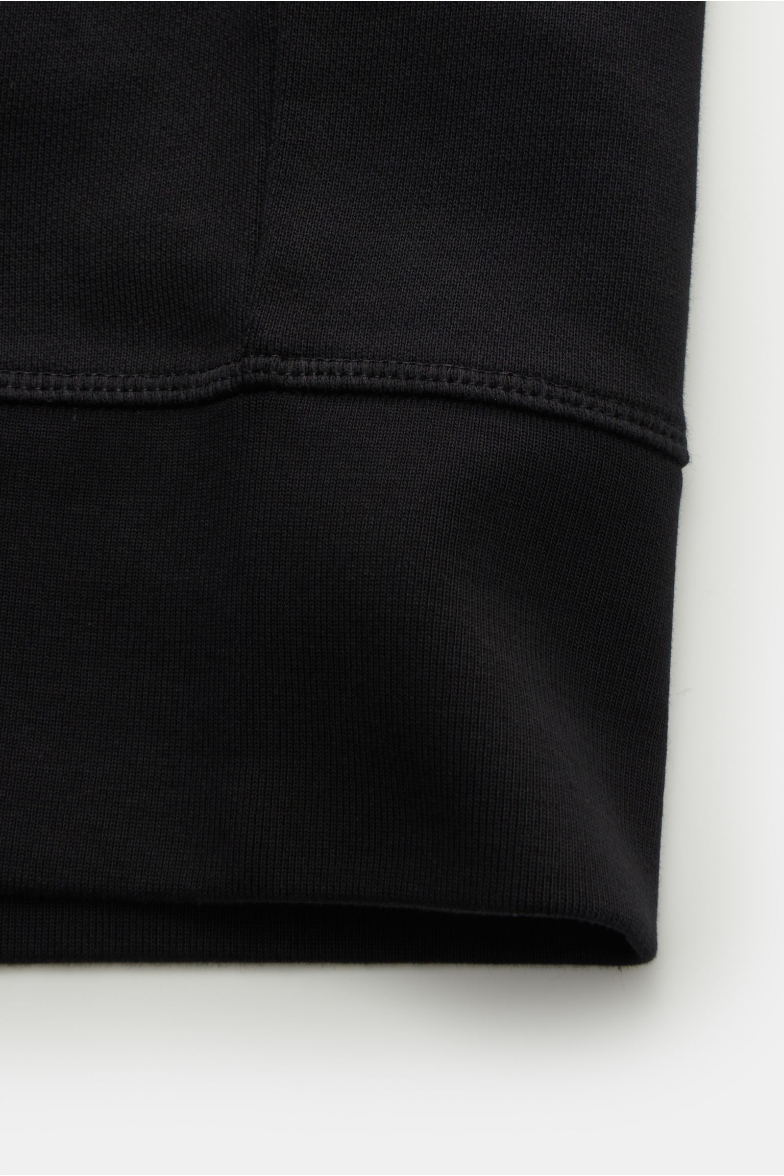 Black close-up of fabric and stitching details on the cuff of the Canada Goose Sweatjacke 'Huron' schwarz, photographed from a side angle. Features: Sweat aus reiner Baumwolle, weicher Griff, Regular Fit, robuster Reißverschluss, Kapuze mit Tunnelzug, get