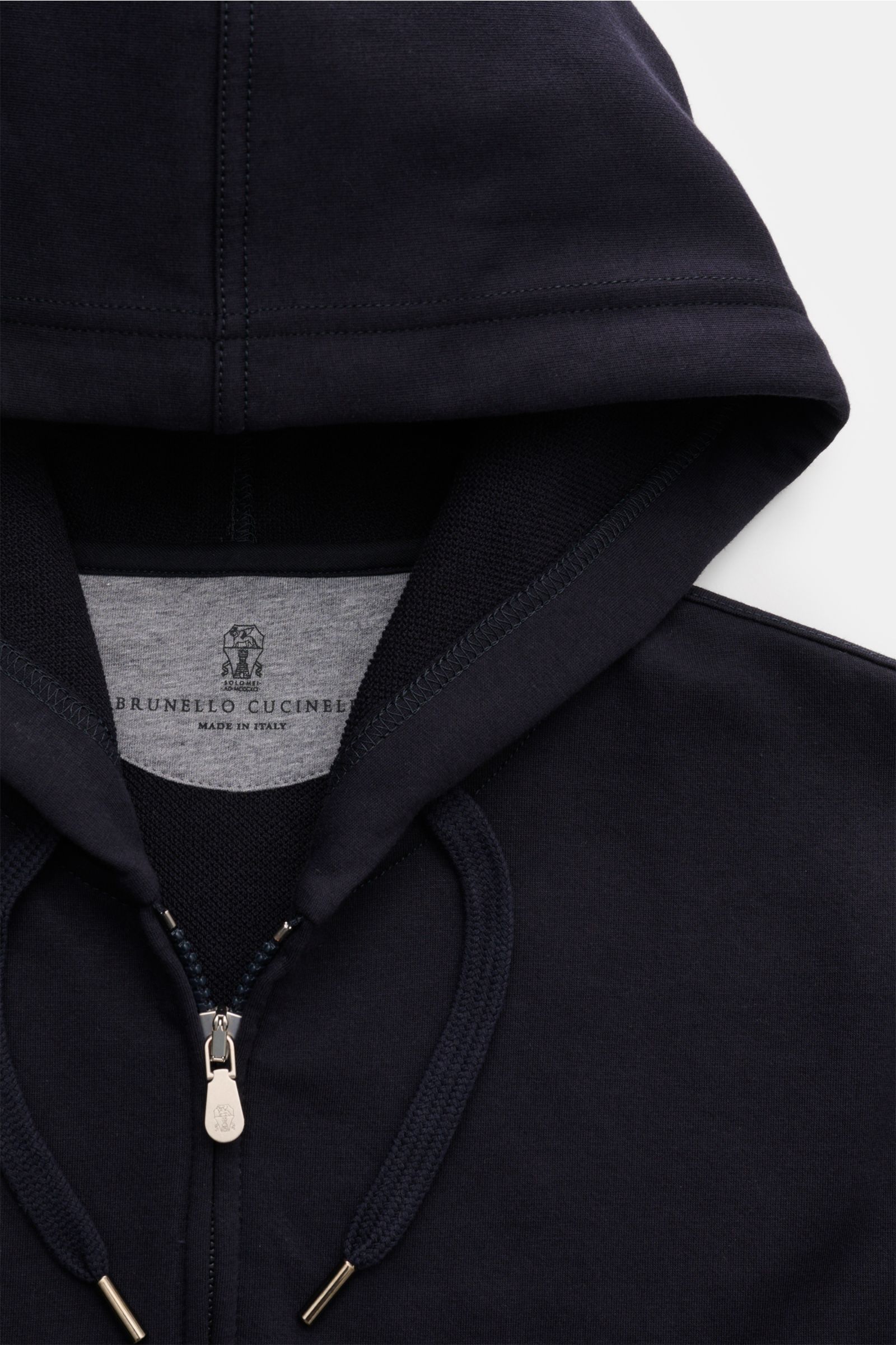 Close-up front view of the Brunello Cucinelli Sweatjacke navy hoodie showing the hood, drawstrings, and zipper with logo detail.

Diese leichte Sweatjacke von BRUNELLO CUCINELLI aus komfortabler Baumwolle verleiht jedem Look einen Hauch von Luxus und s