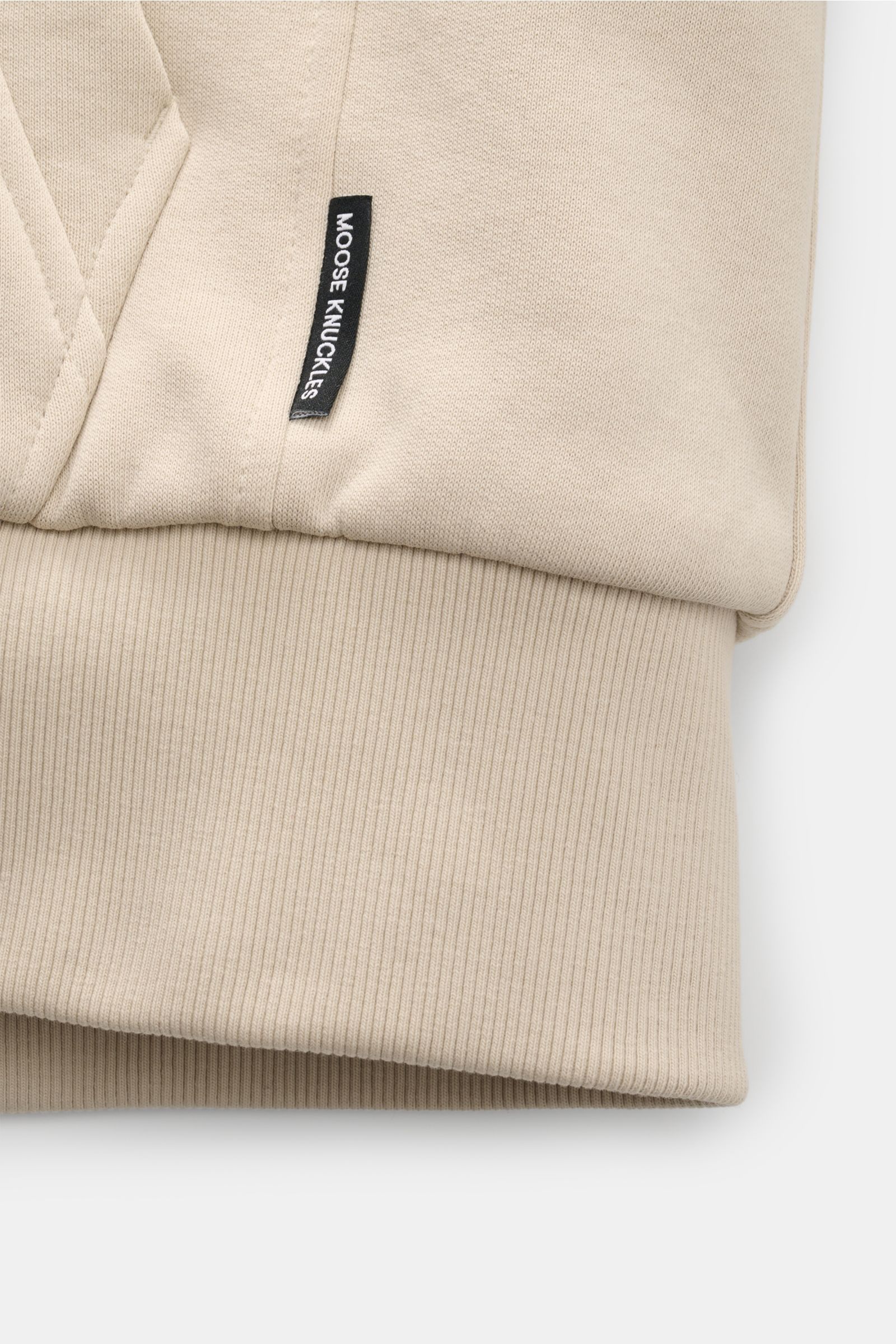 Alt tag (125 characters max): Close-up front view of Moose Knuckles Sweatjacke 'Classic Bunny' creme showing pocket, ribbed cuff, and logo label.

Description: Perfekt für kalte Tage: Dank der leichten Wattierung und einer Kapuze mit abnehmbarem Faux-F