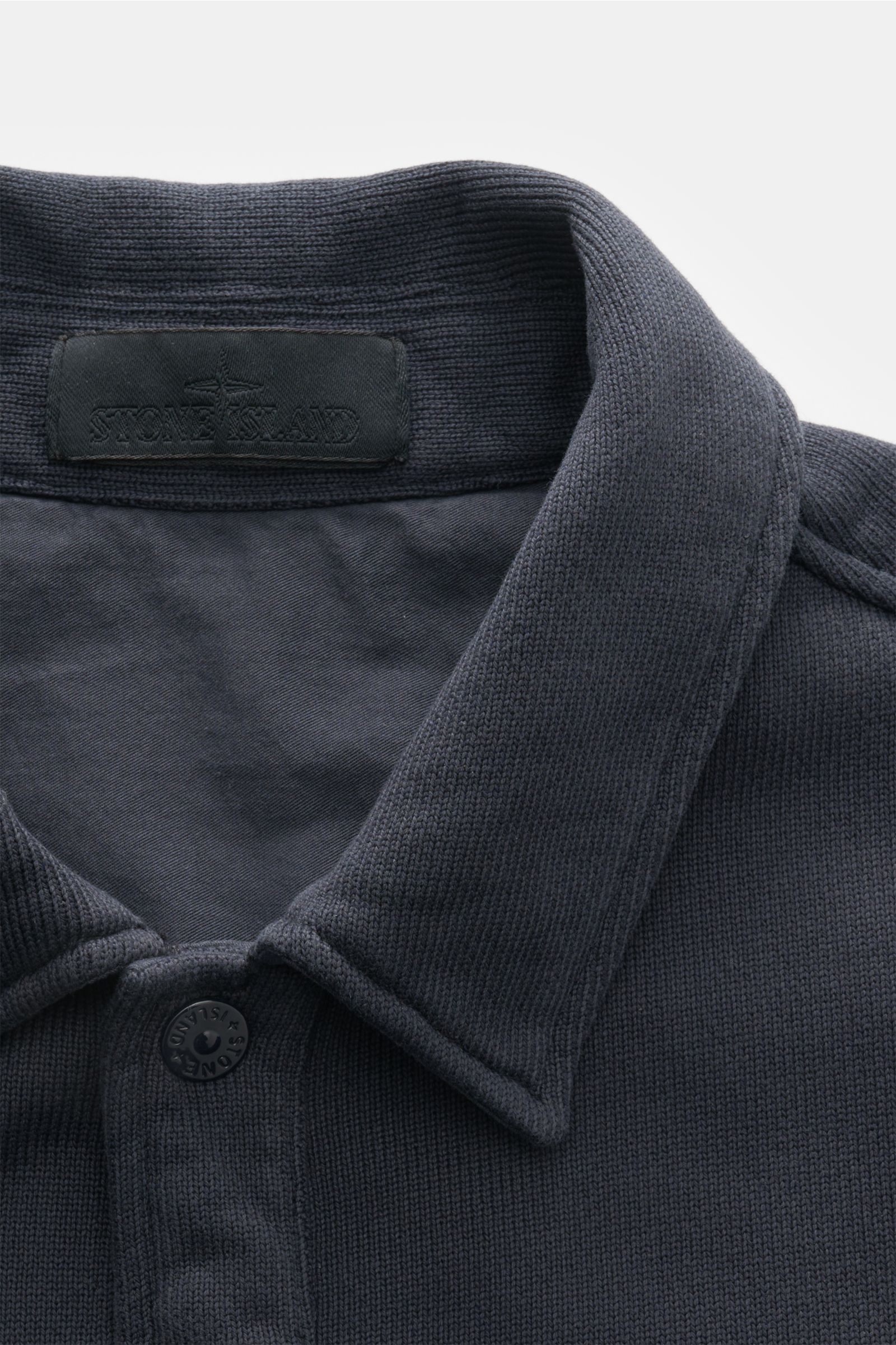 Nahaufnahme aus schräger Perspektive der Stone Island Sweatjacke 'Ghost' navy mit Umlegekragen, Knopfverschluss und feinem Strickbild.