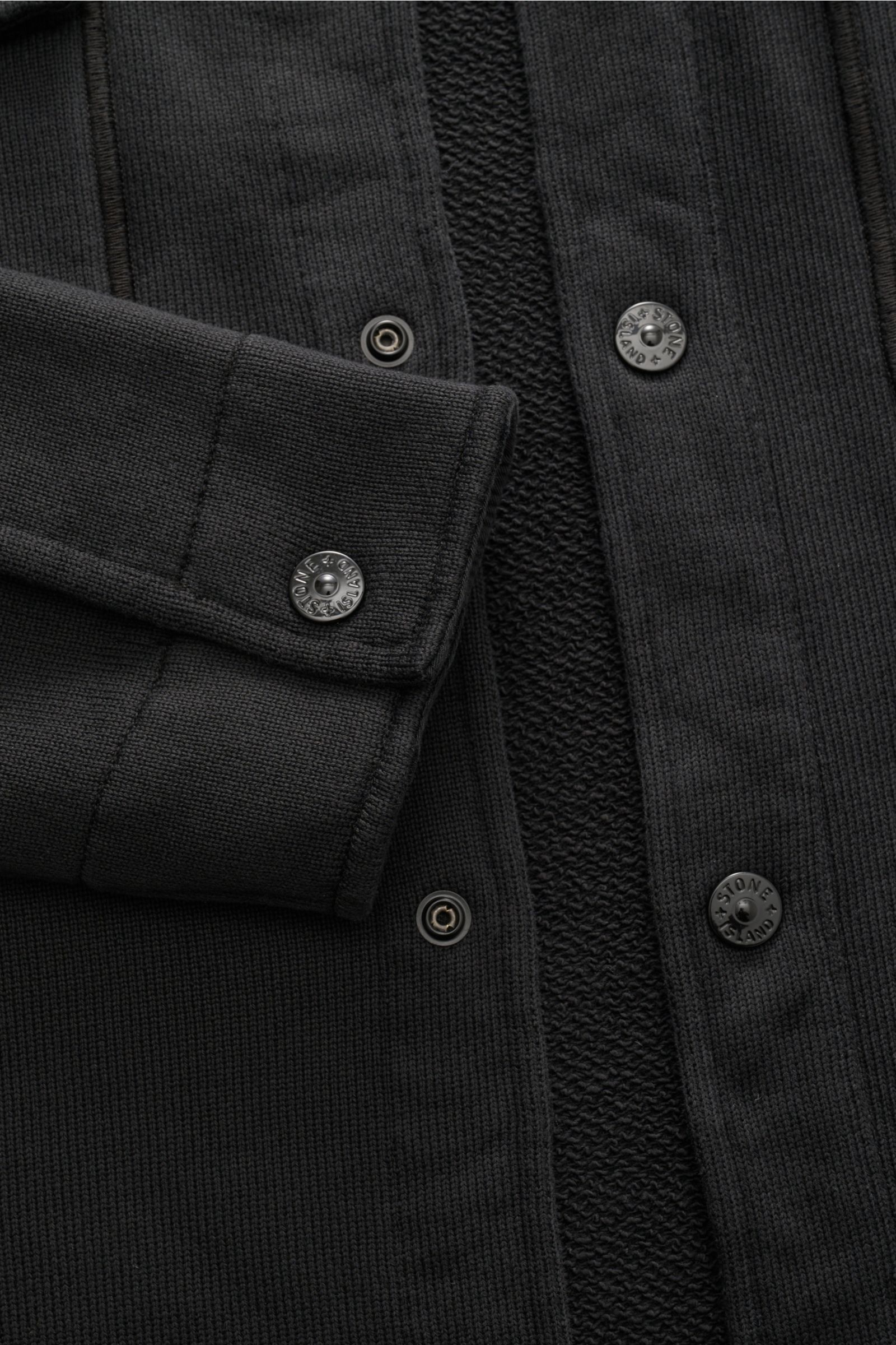 Nahaufnahme der Stone Island Sweatjacke 'Ghost' schwarz aus der Frontperspektive, zeigt Baumwollqualität, Regular Fit, Umlegekragen, Kompass-Badge am Ärmel und Manschetten.