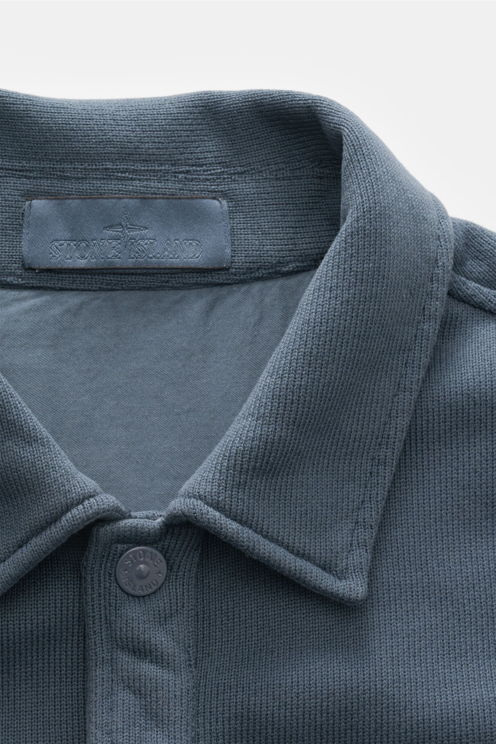 Nahaufnahme der Stone Island Sweatjacke 'Ghost' graublau mit Umlegekragen, Knopf und feinem Strickbild aus reiner Baumwolle.